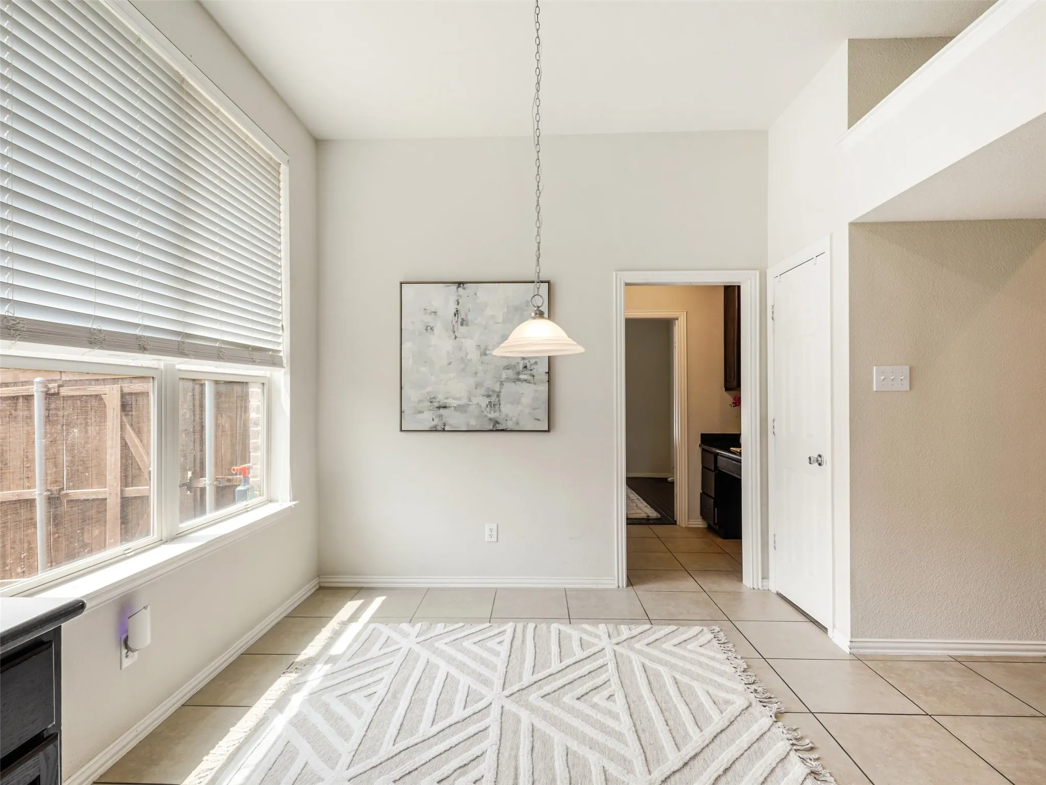 Light-filled breakfast area with tile flooring, a pendant light, and ample space for everyday dining.