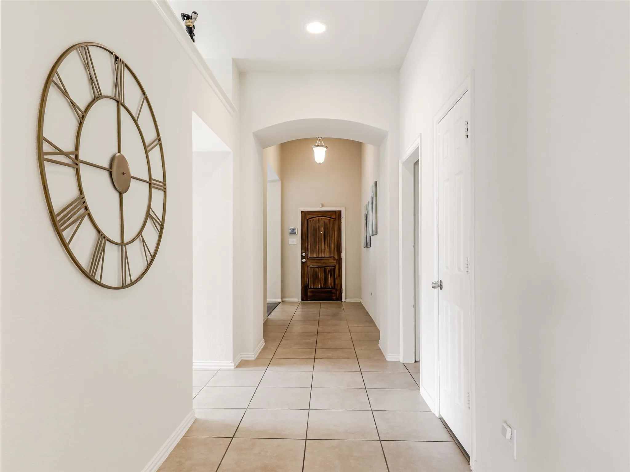 Extended entryway with high ceilings, arched architectural details, neutral finishes, and easy-care tile flooring.