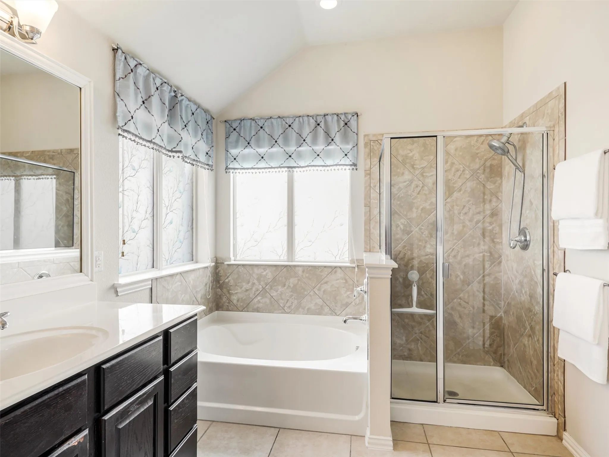 Generous dual-sink vanity offers abundant counter space, ample cabinetry, an oversized mirror, and access to the walk-in closet.