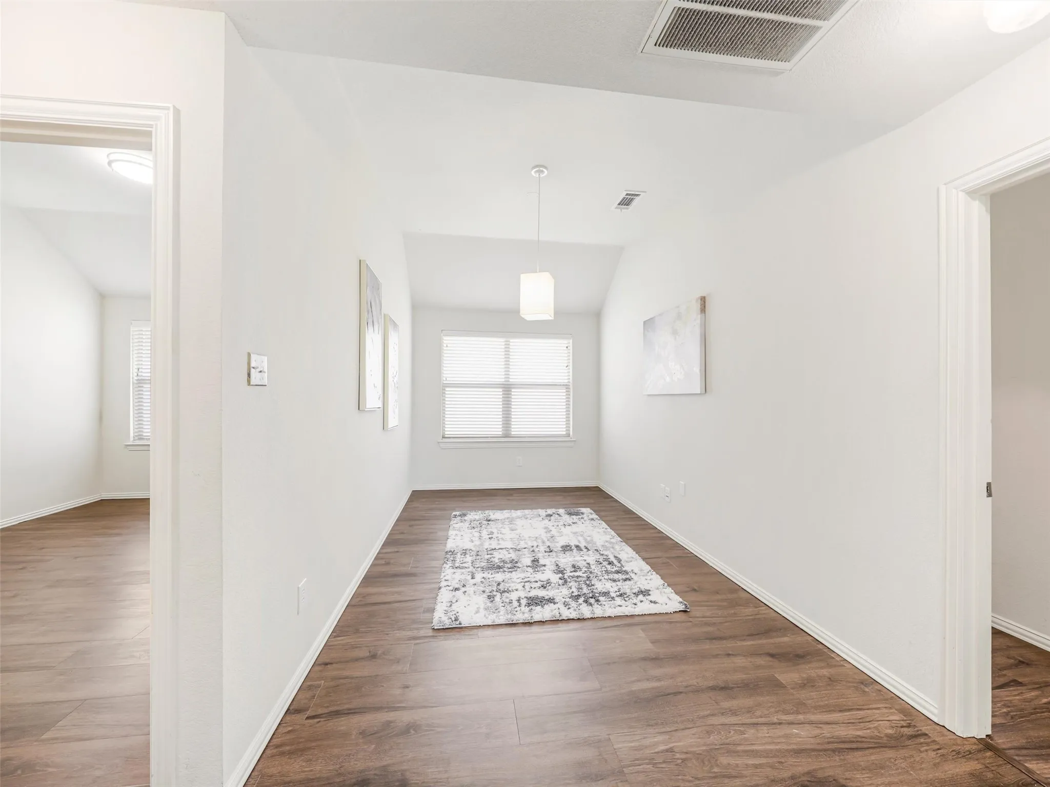 Versatile bonus area with wood-look flooring, a pendant light, and access to surrounding rooms—ideal for a study, homework station, or reading space.