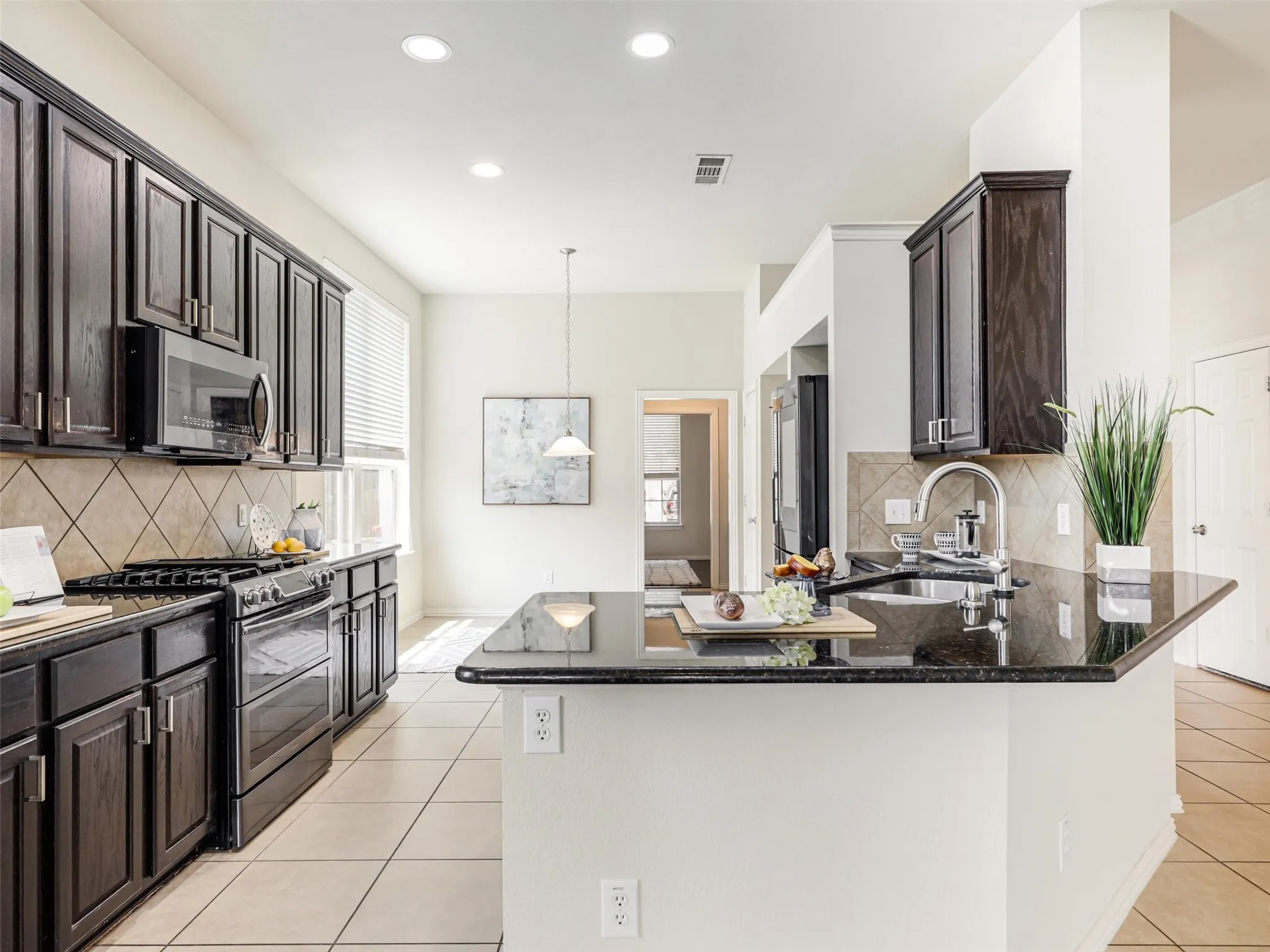 Chef delight kitchen with rich cabinetry, granite countertops, tile backsplash, stainless steel appliances, and generous counter space.