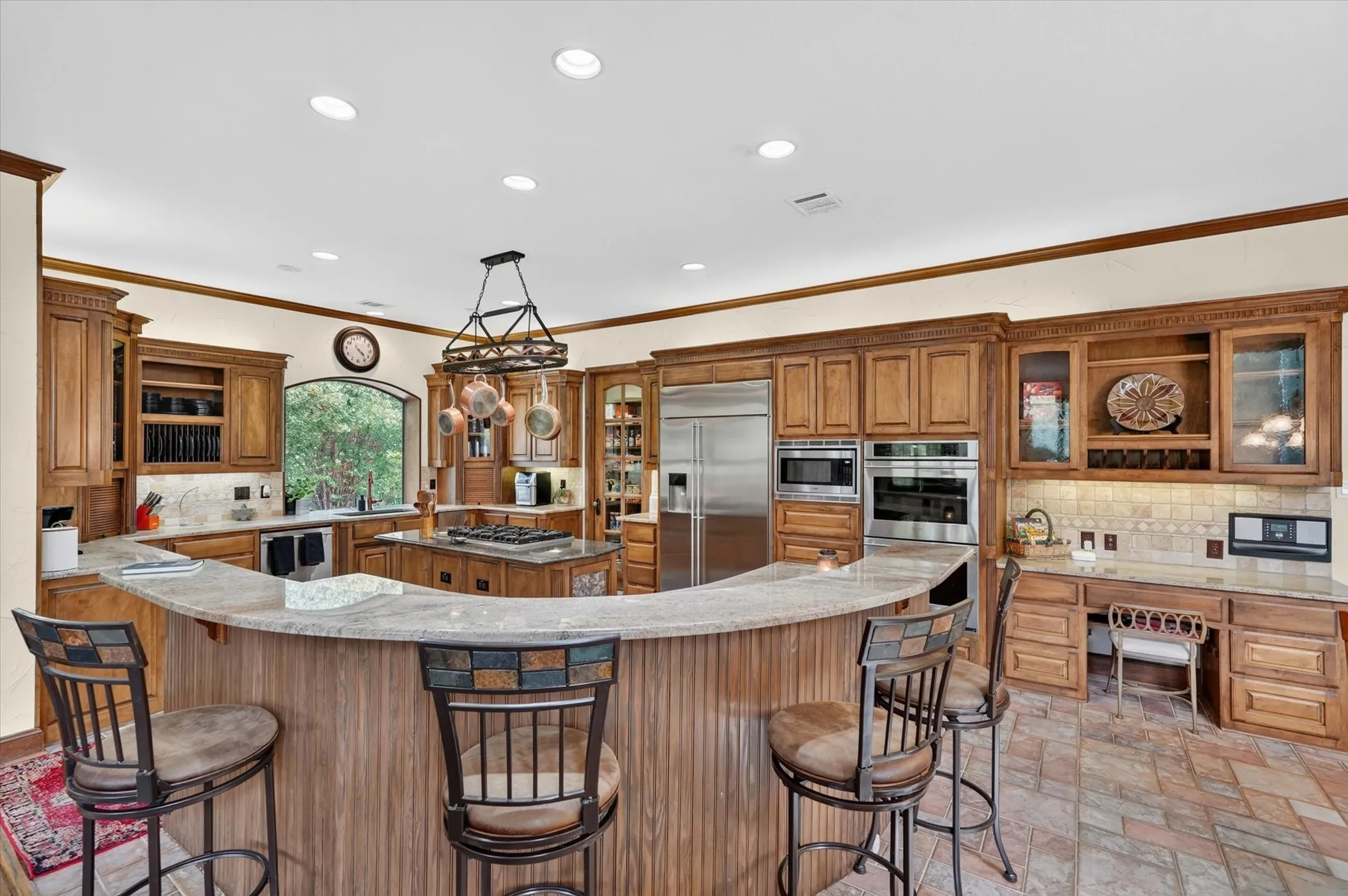 The chef’s kitchen serves as the heart of the residence, equipped with granite countertops, high-end stainless steel appliances including a built-in fridge, double appliance garages, a built-in wine rack, island, walk-in pantry, and a convenient planning center.
