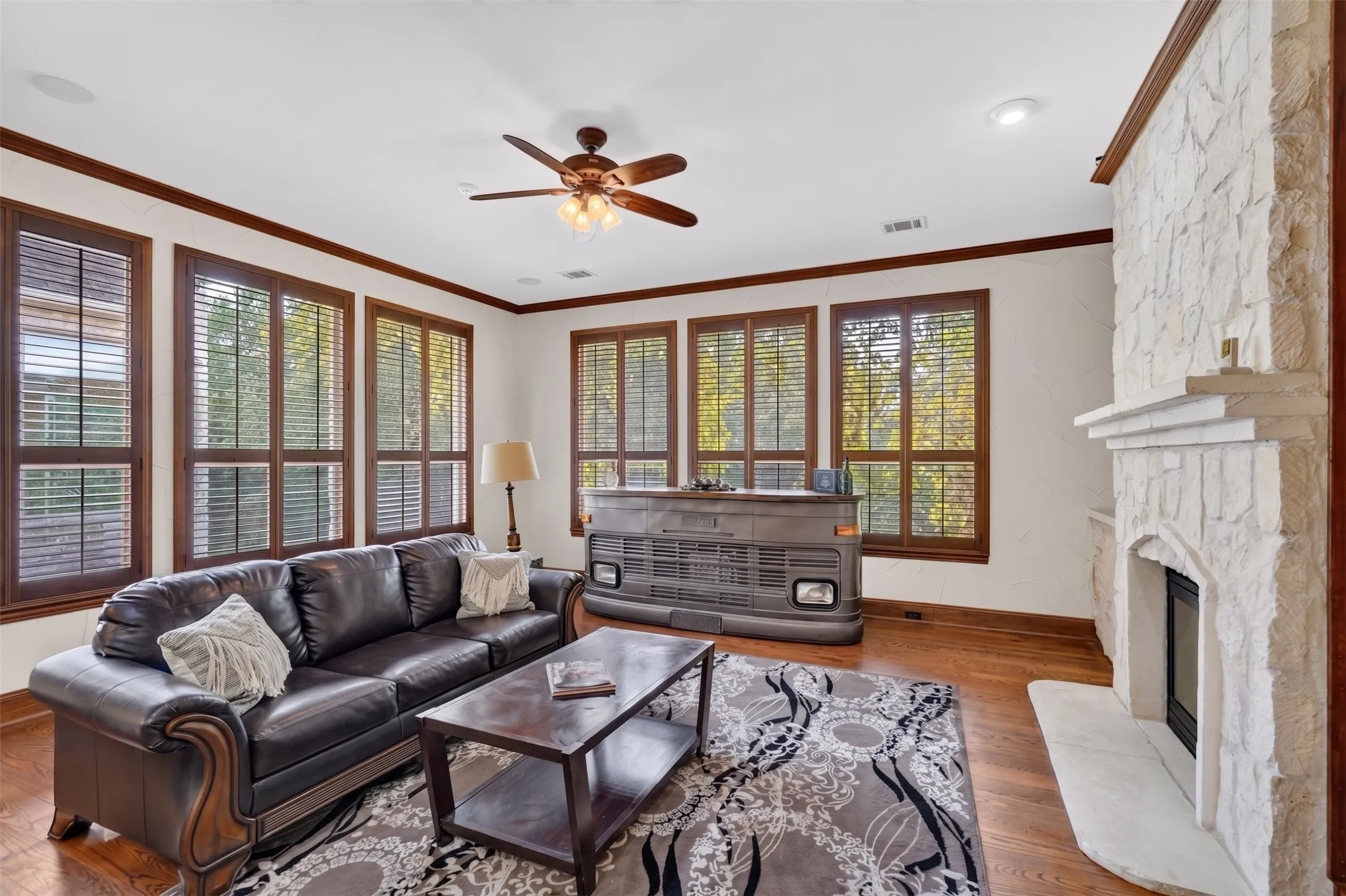 Sunlight pours through abundant windows, illuminating a sun-drenched floor plan anchored by a cozy family room with a gorgeous floor-to-ceiling stone fireplace.