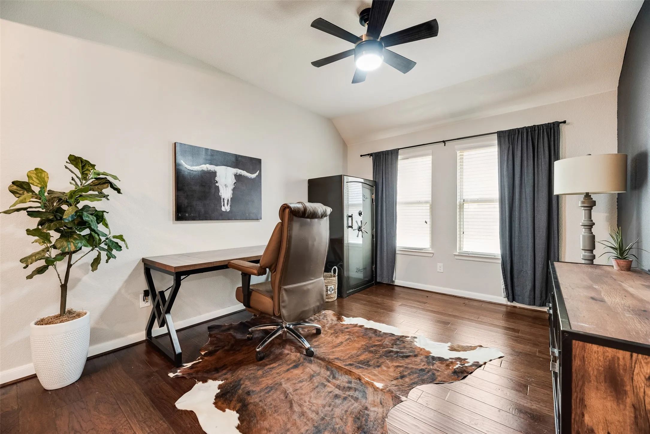 Vaulted ceiling, wood-finish flooring, ceiling fan with integrated lighting, multiple windows with blinds, and built-in storage