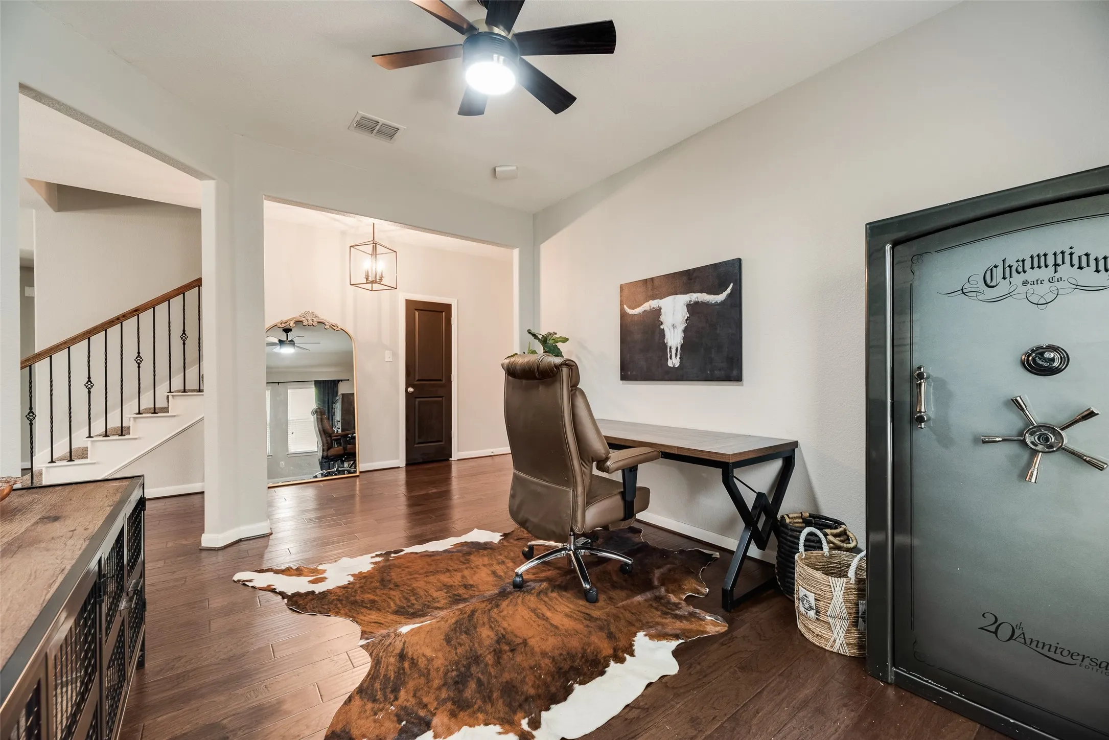 Wood-finish flooring, staircase with wrought iron balusters, recessed lighting, ceiling fan light fixture, and a built-in safe