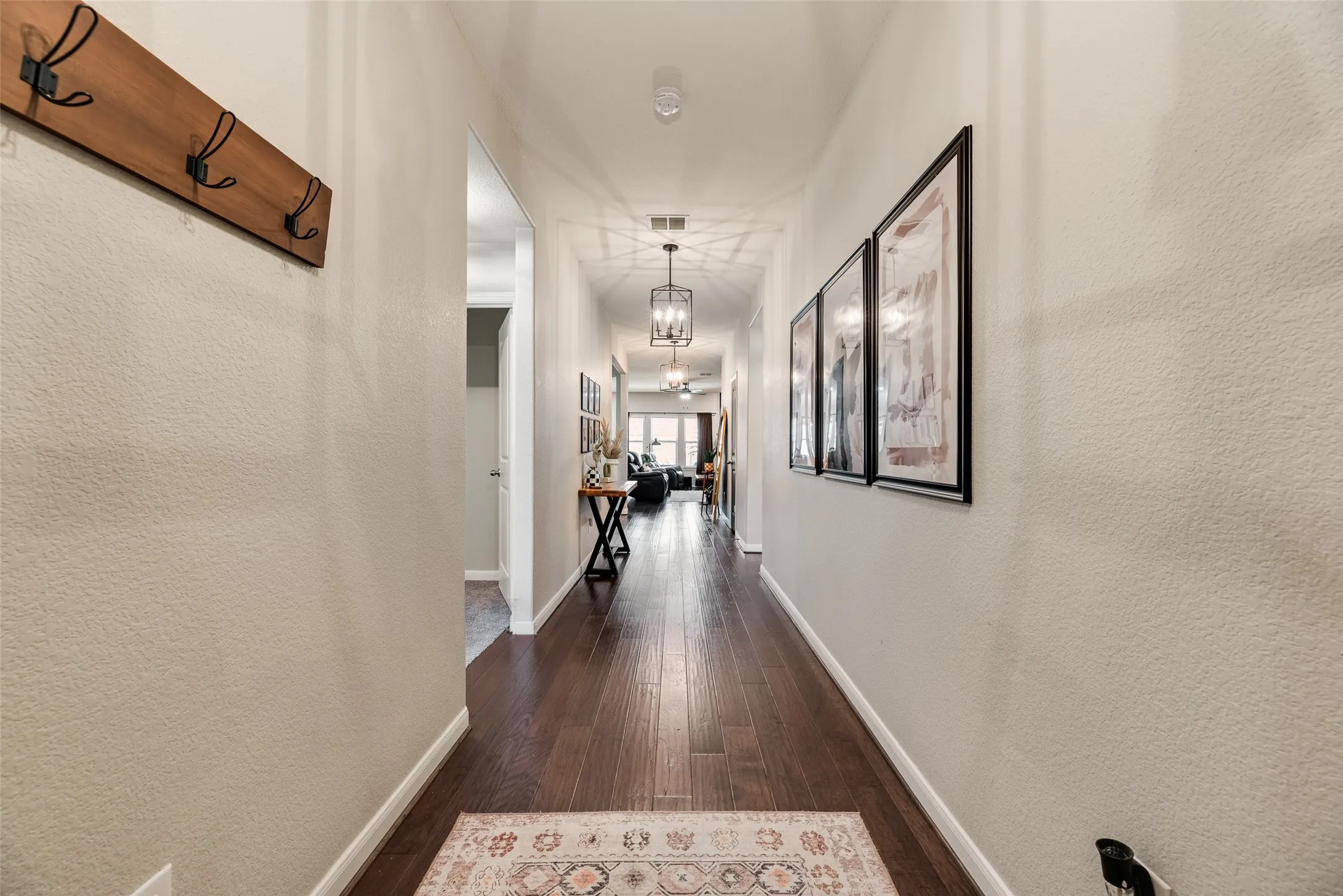 Long hallway with dark wood-finish flooring, light neutral wall paint, and recessed lighting