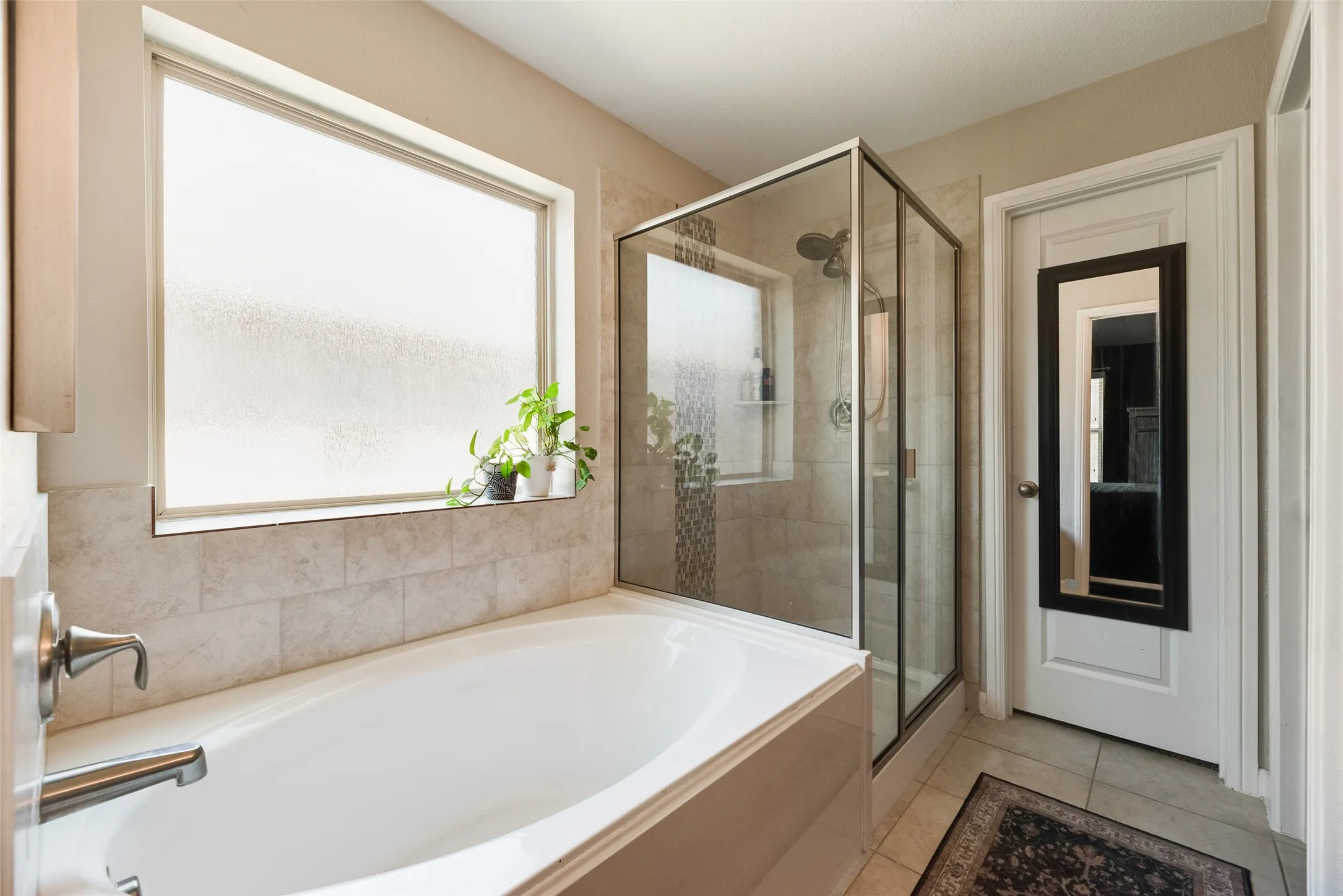 Built-in soaking tub, glass-enclosed shower, and frosted privacy window