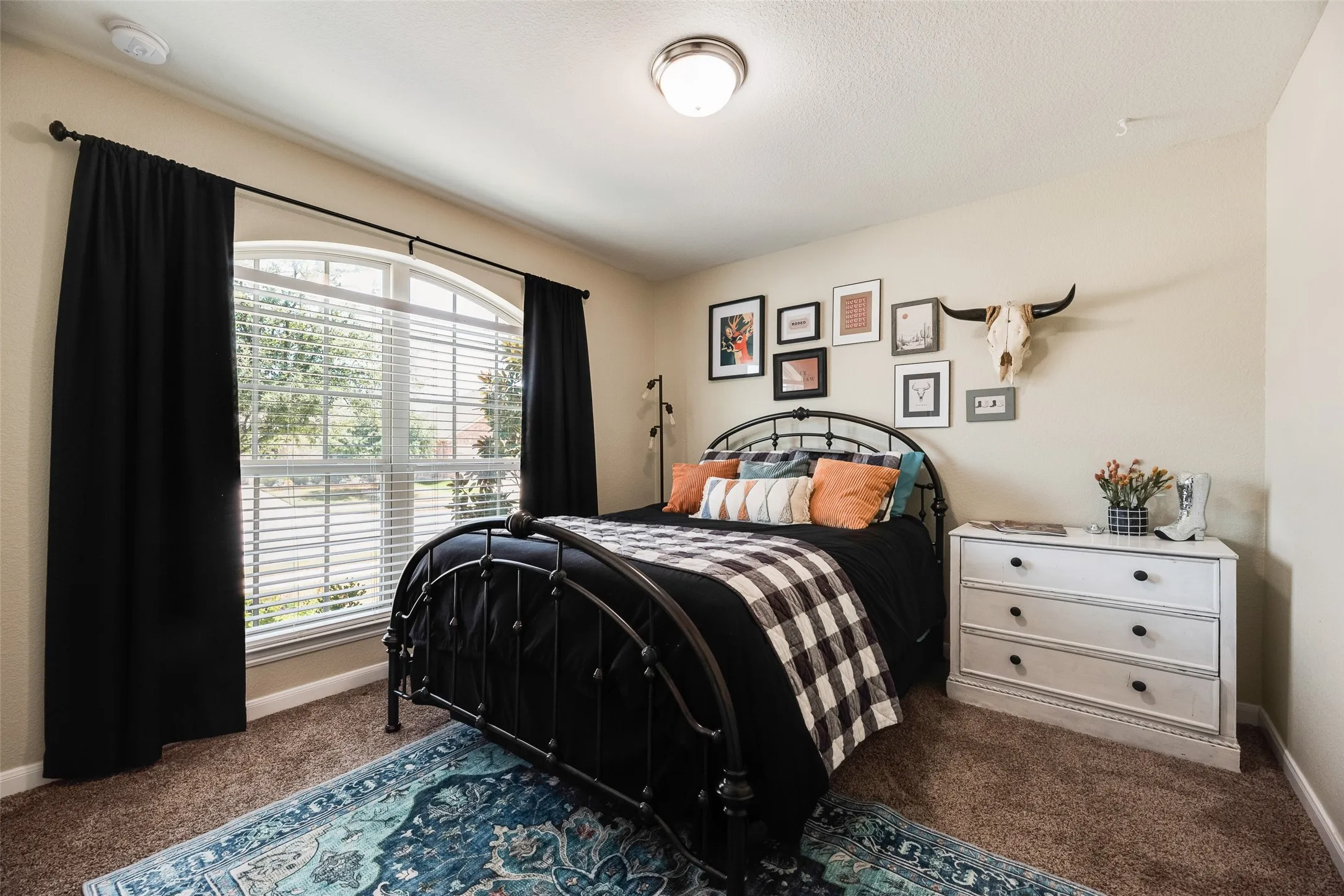 Arched window with blinds and dark curtains, complemented by a semi-flush mount ceiling light