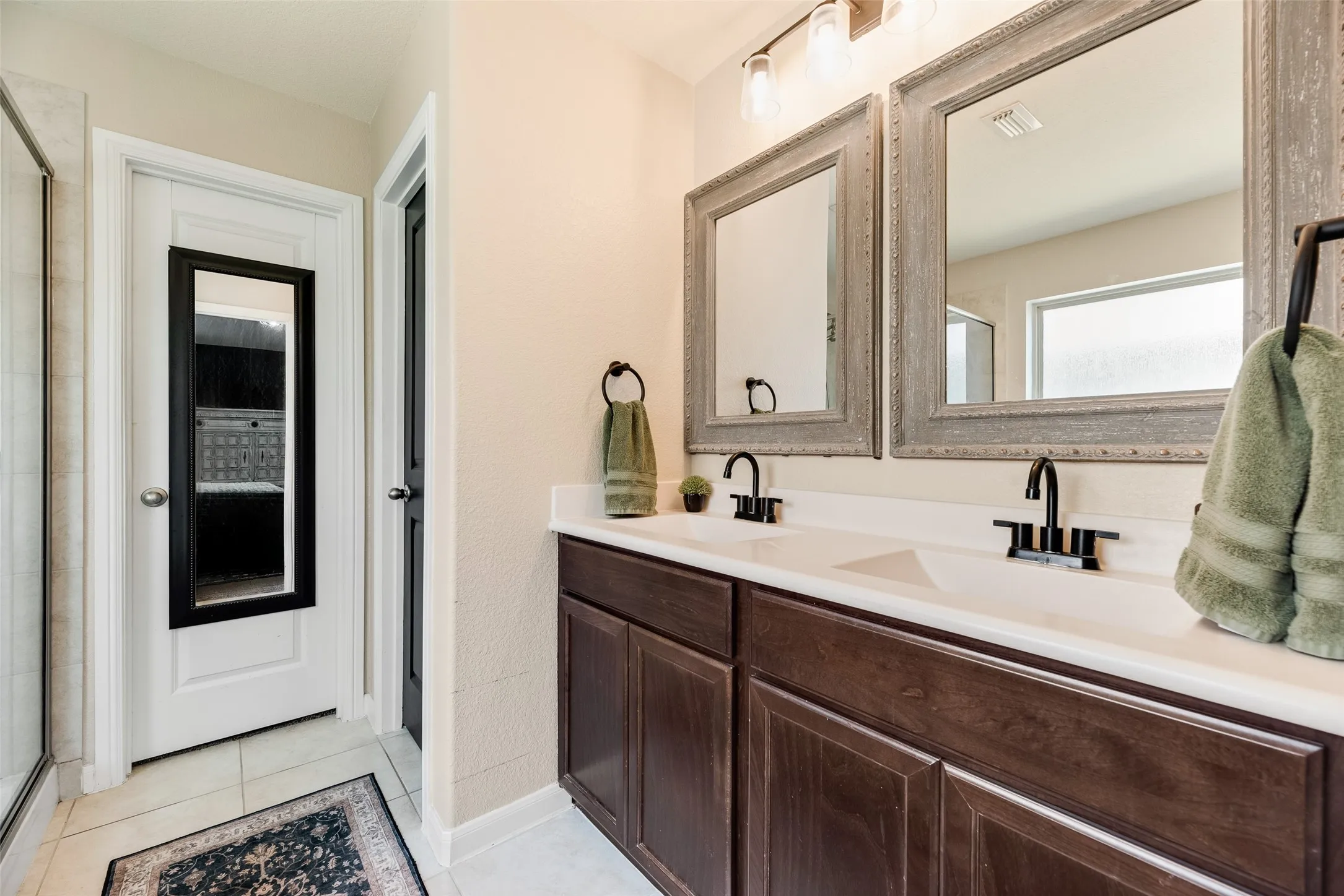 Dual vanity with dark wood-finish cabinetry, white countertop, two undermount sinks, and matte black faucets
