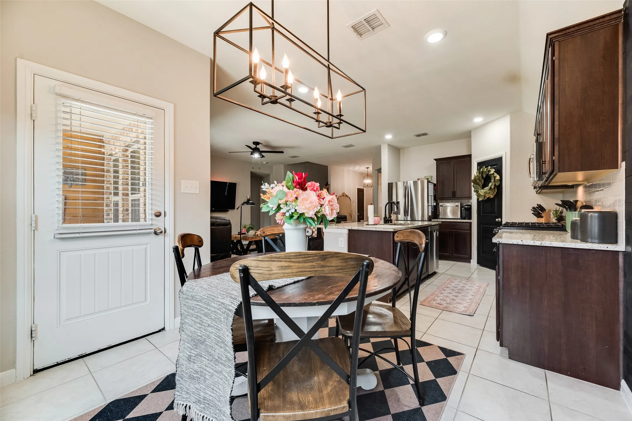 Open-concept kitchen with dark wood-finish cabinetry, light-toned countertops, and stainless steel appliances