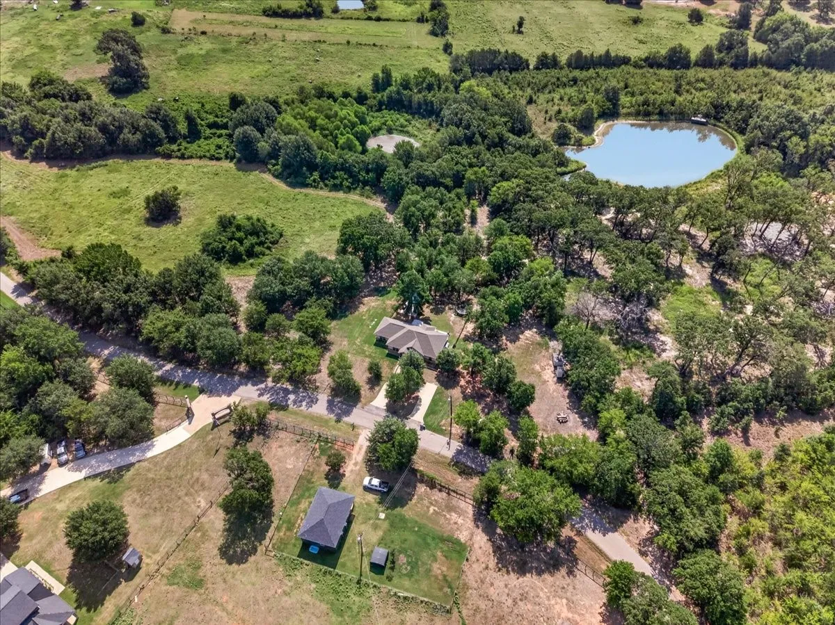 Expansive property featuring a residence, detached structure, two ponds, mature trees, and a paved driveway