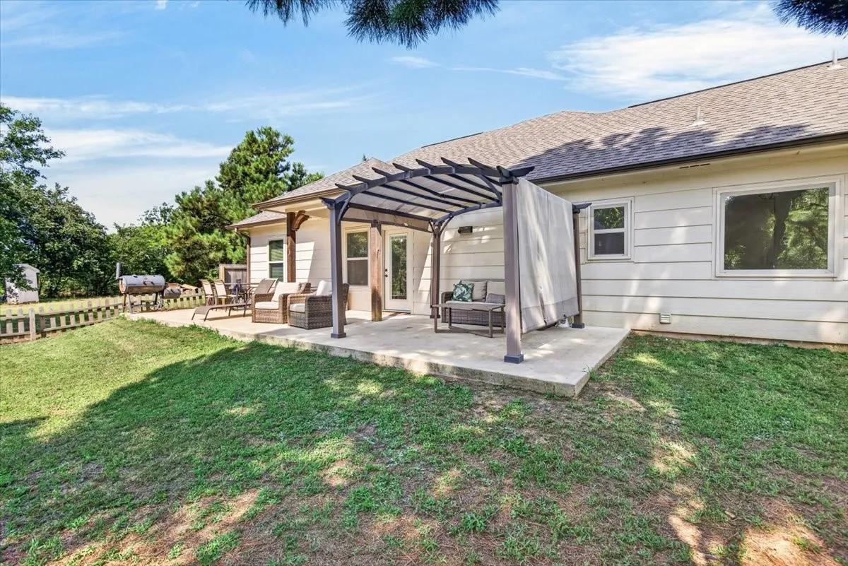Expansive concrete patio featuring a pergola with a canopy, dual-pane windows, and a shingled roof