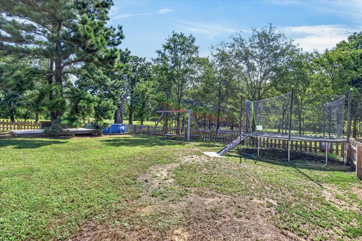 Expansive outdoor area with a wooden fence, mature trees, and a raised wooden deck