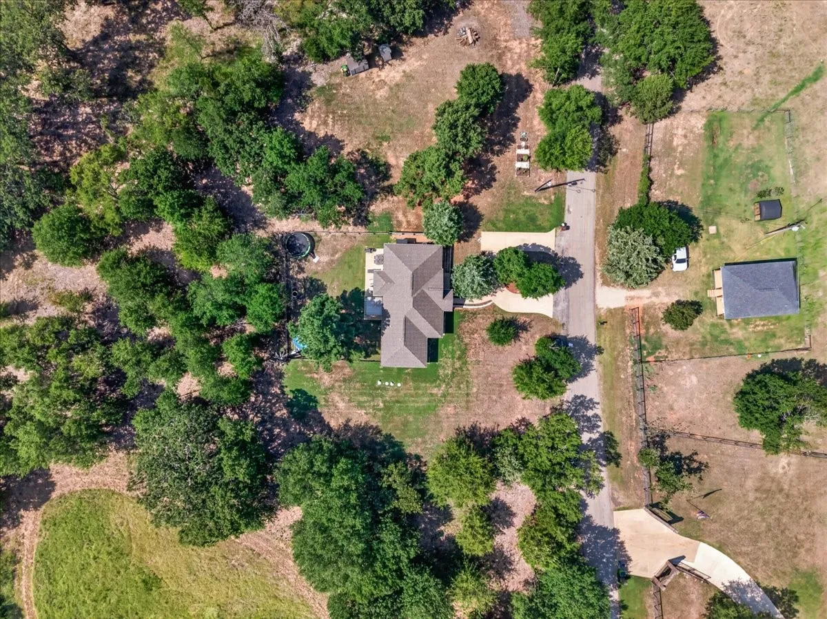 Expansive lot featuring mature trees, a driveway, and a residential structure with a shingle roof