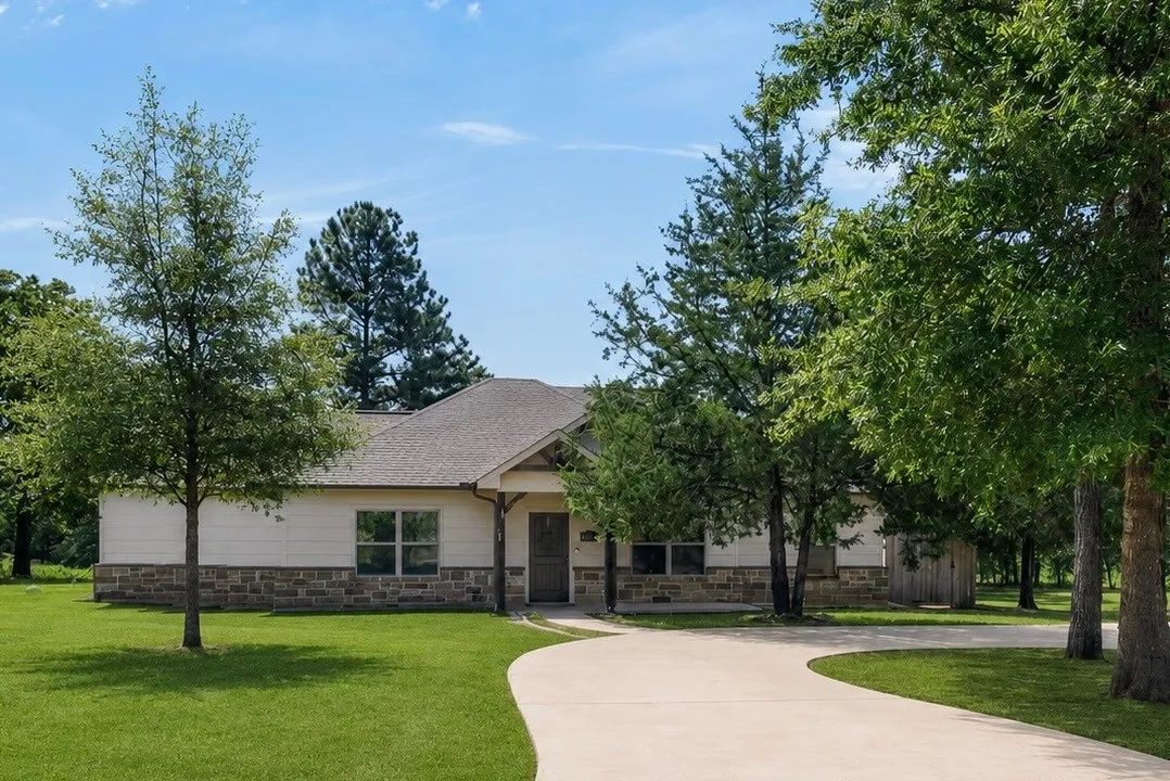 Single-story residence featuring a partial stone facade, covered entry, and a curved concrete driveway