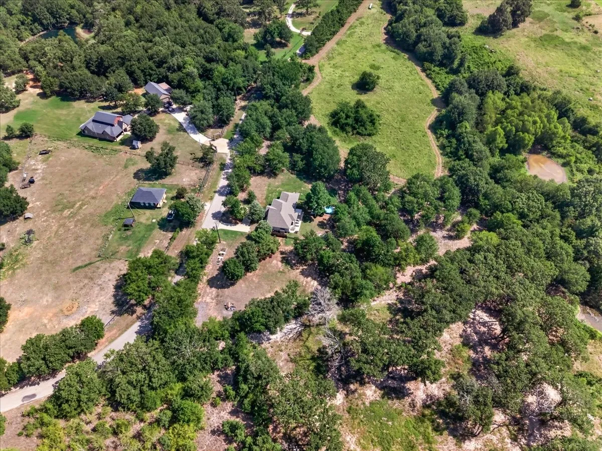 Expansive lot with multiple structures, surrounded by mature trees and natural landscaping
