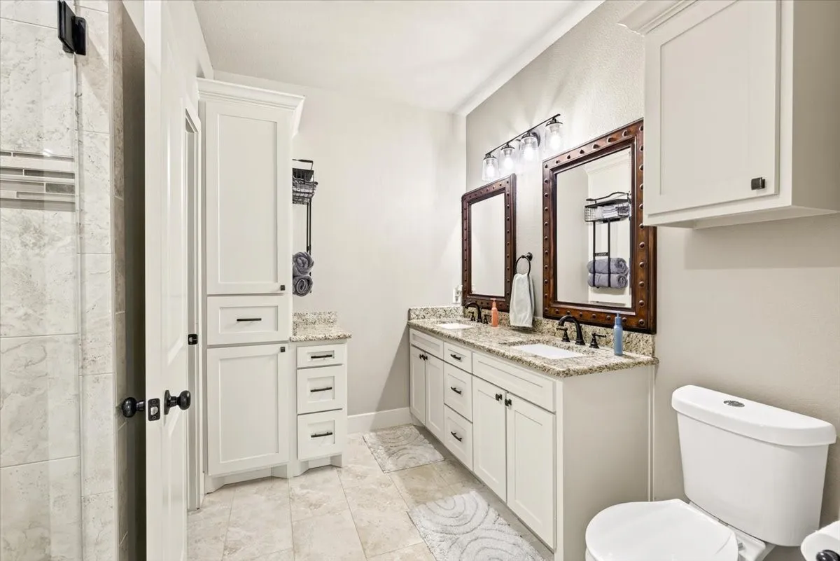 Dual vanity with granite countertops, undermount sinks, and matte black fixtures