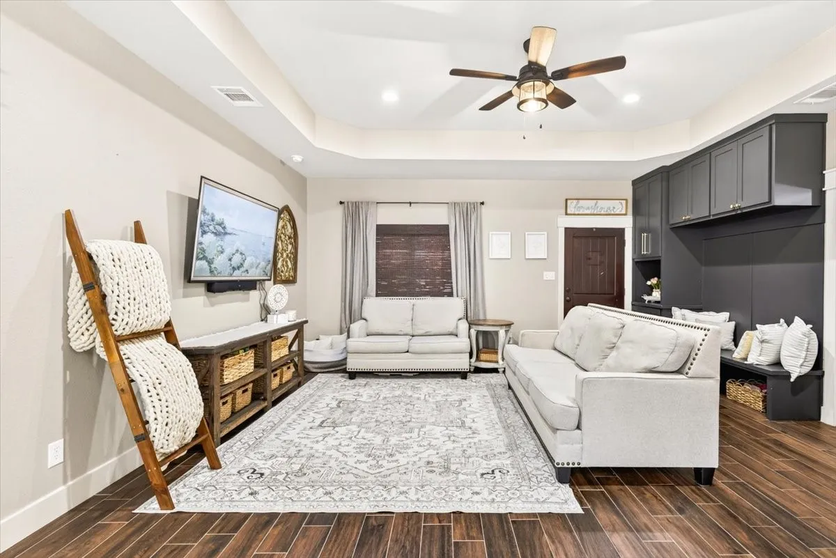 Recessed lighting, wood-look flooring, ceiling fan, built-in cabinetry, and tray ceiling