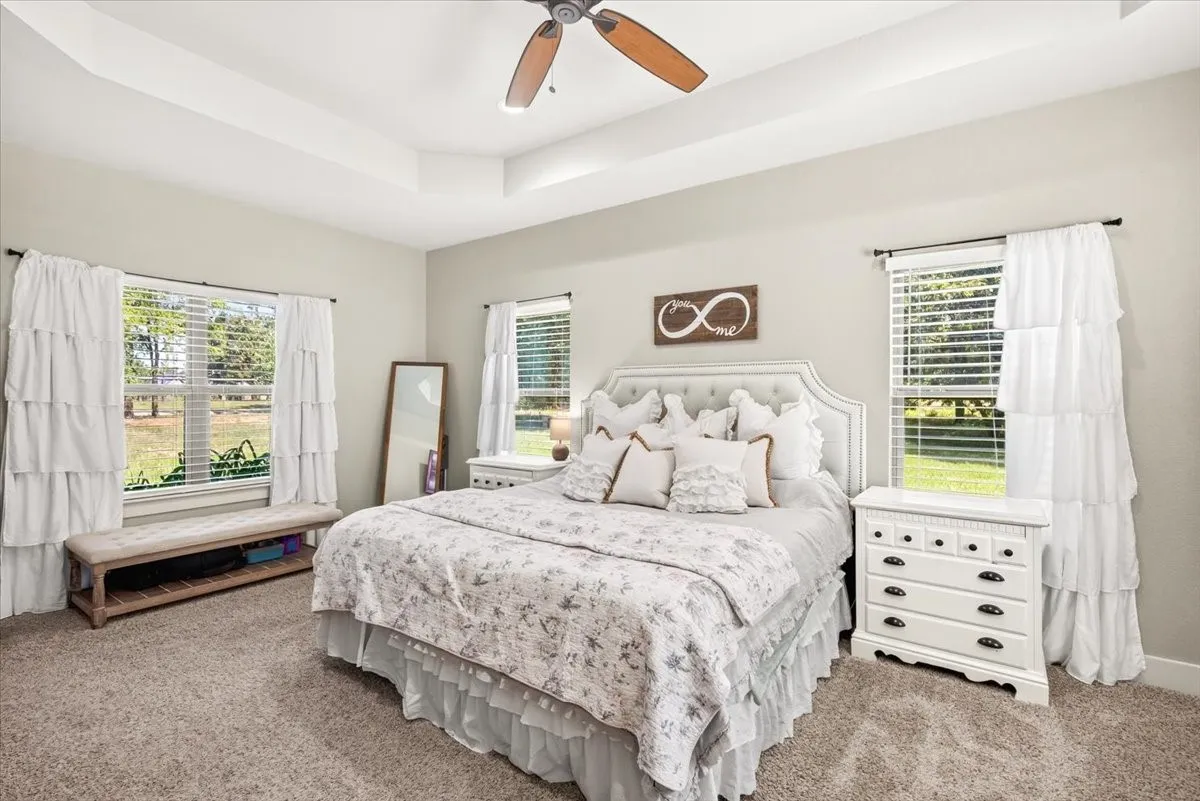 Tray ceiling with a ceiling fan, light gray wall paint, and carpeted flooring
