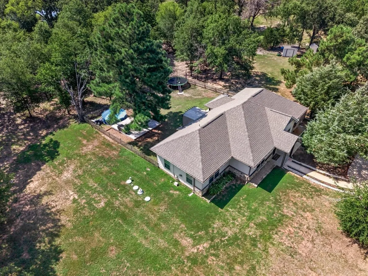 Spacious property with a shingle roof, mature trees, and an in-ground swimming pool