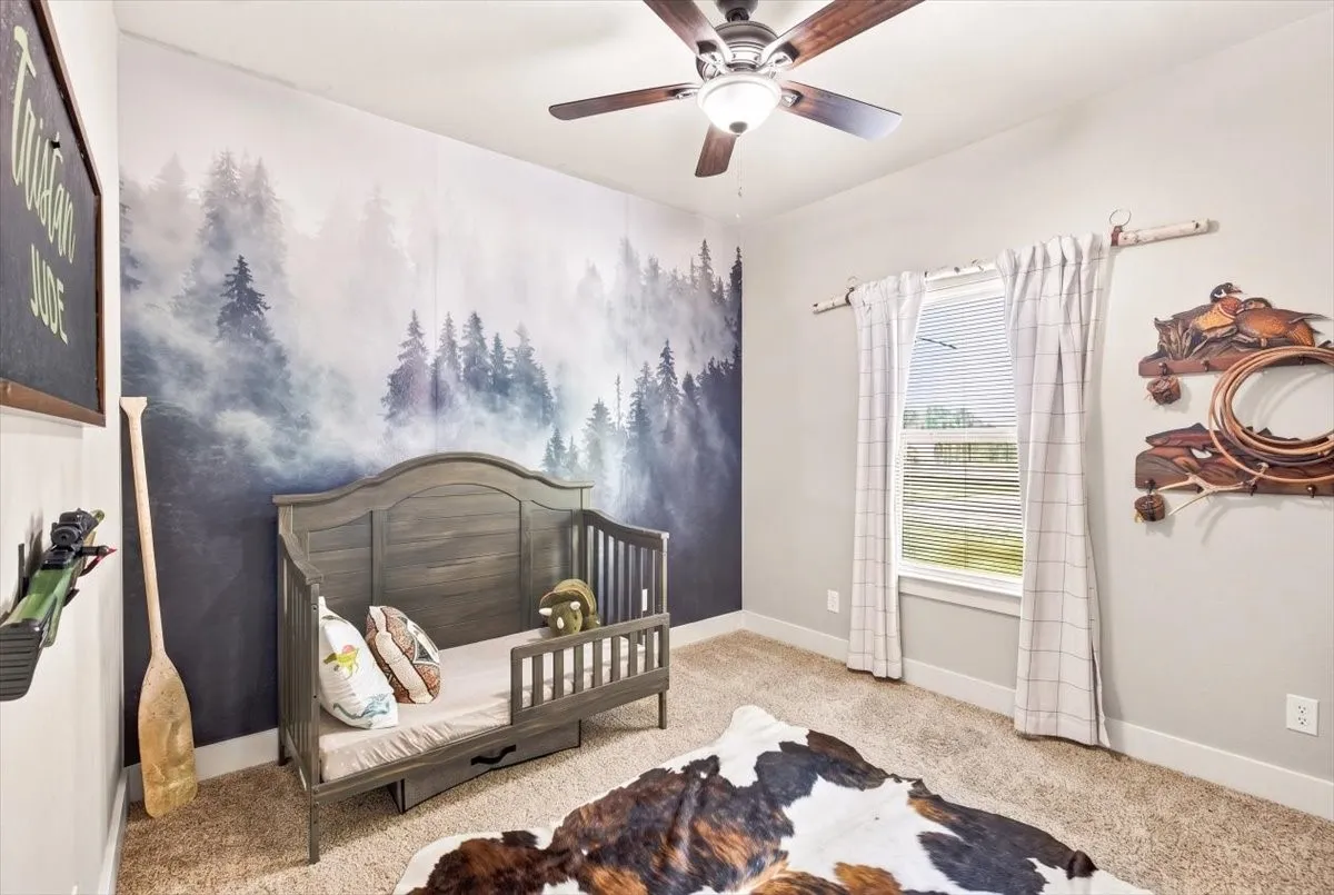 Carpeted room featuring a ceiling fan, a window with blinds, and a decorative wall covering