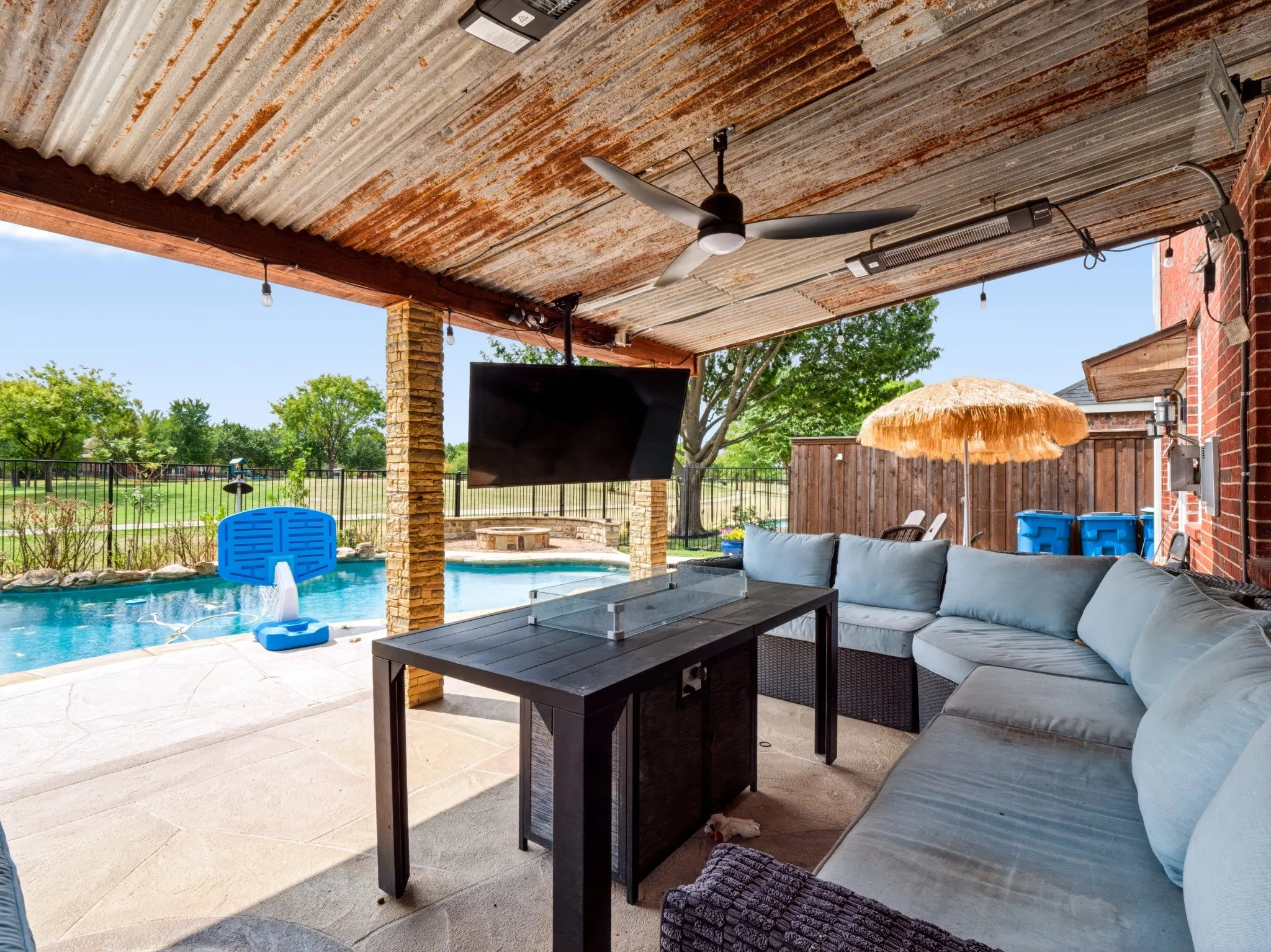 Covered patio with a corrugated metal ceiling, ceiling fan, and mounted outdoor television