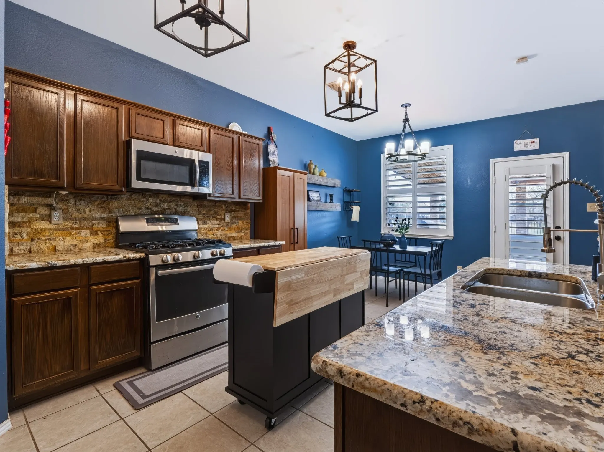 Kitchen featuring stainless steel appliances, wood cabinetry, granite countertops, and a tiled backsplash