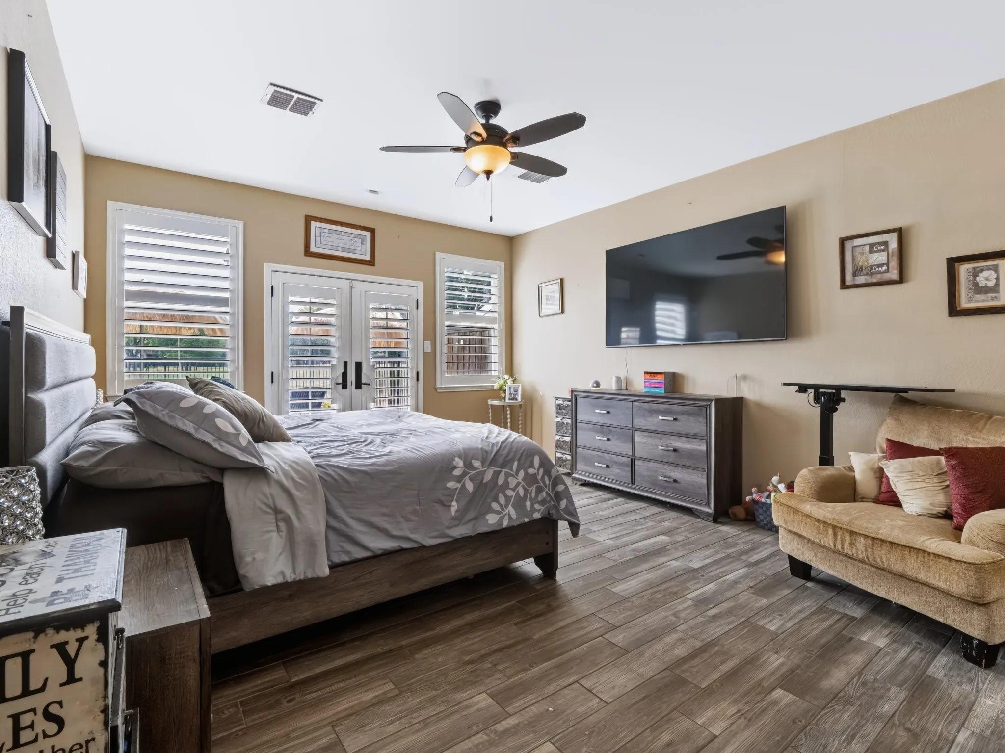 Wood-finish flooring throughout, ceiling fan with integrated lighting, and plantation shutters on multiple windows