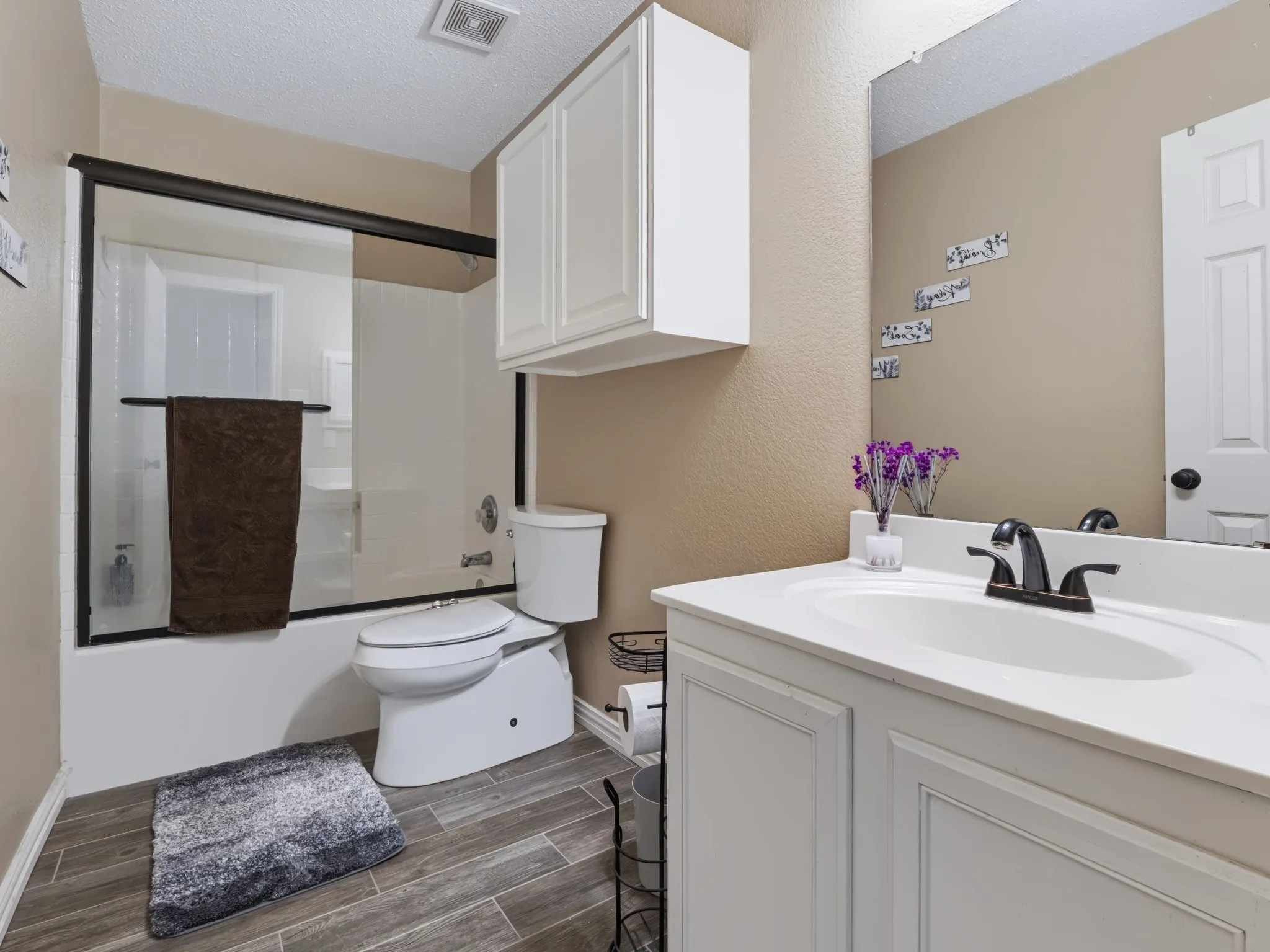 White vanity with integrated sink, bronze-finish faucet, and full-width mirror