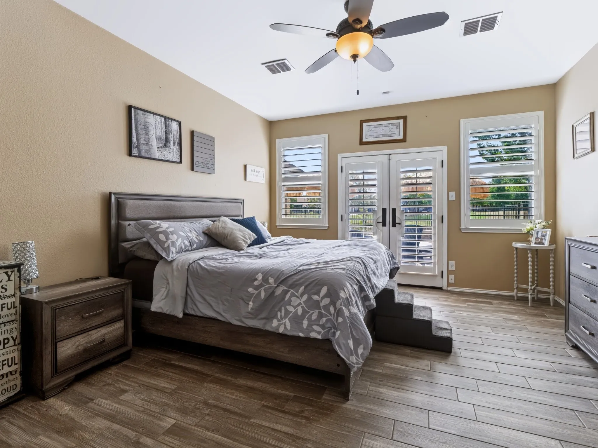 Wood-finish tile flooring, ceiling fan, and double French doors with plantation shutters