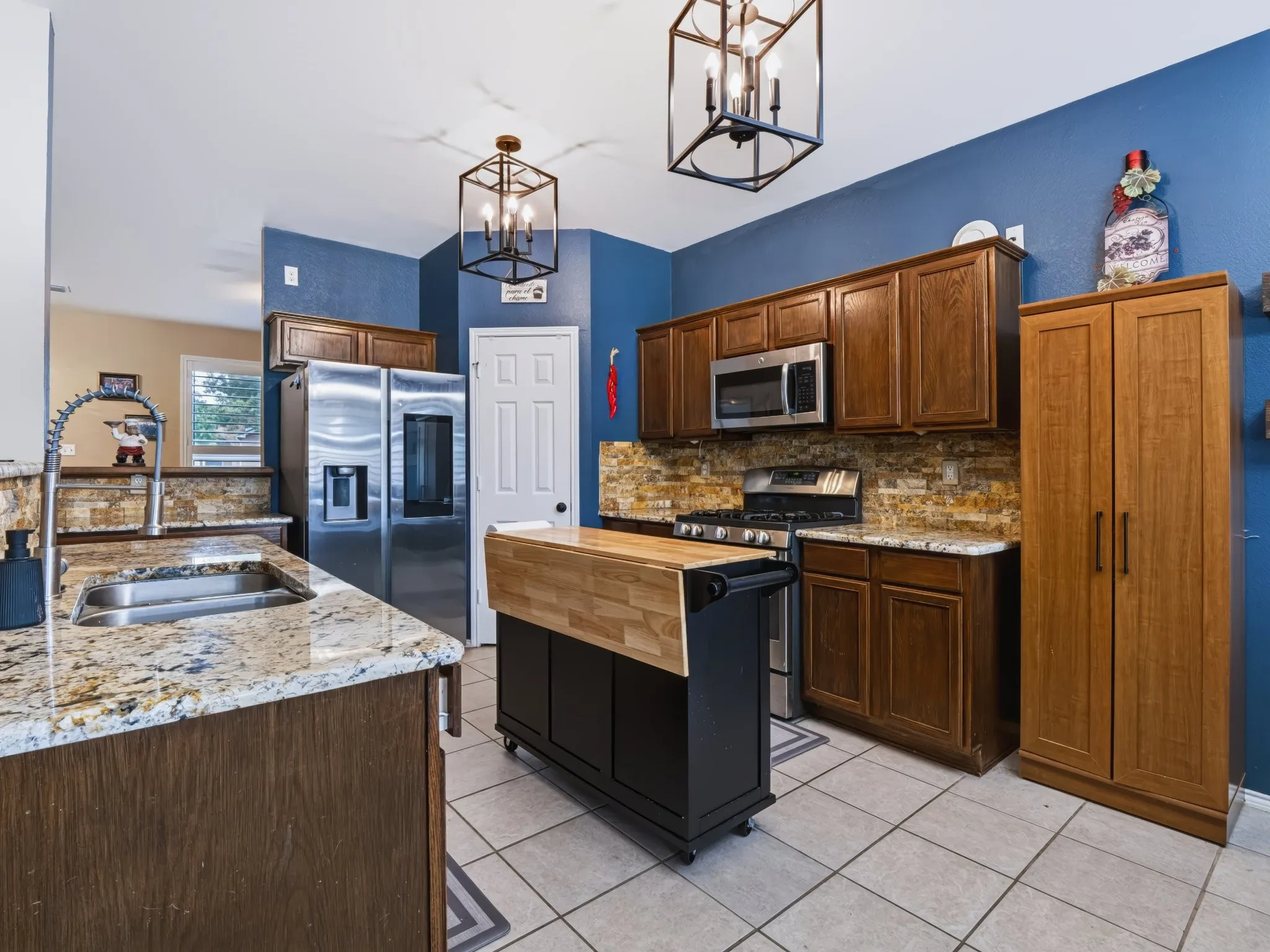 Kitchen featuring granite countertops, wood cabinetry, stainless steel appliances, and a tiled backsplash
