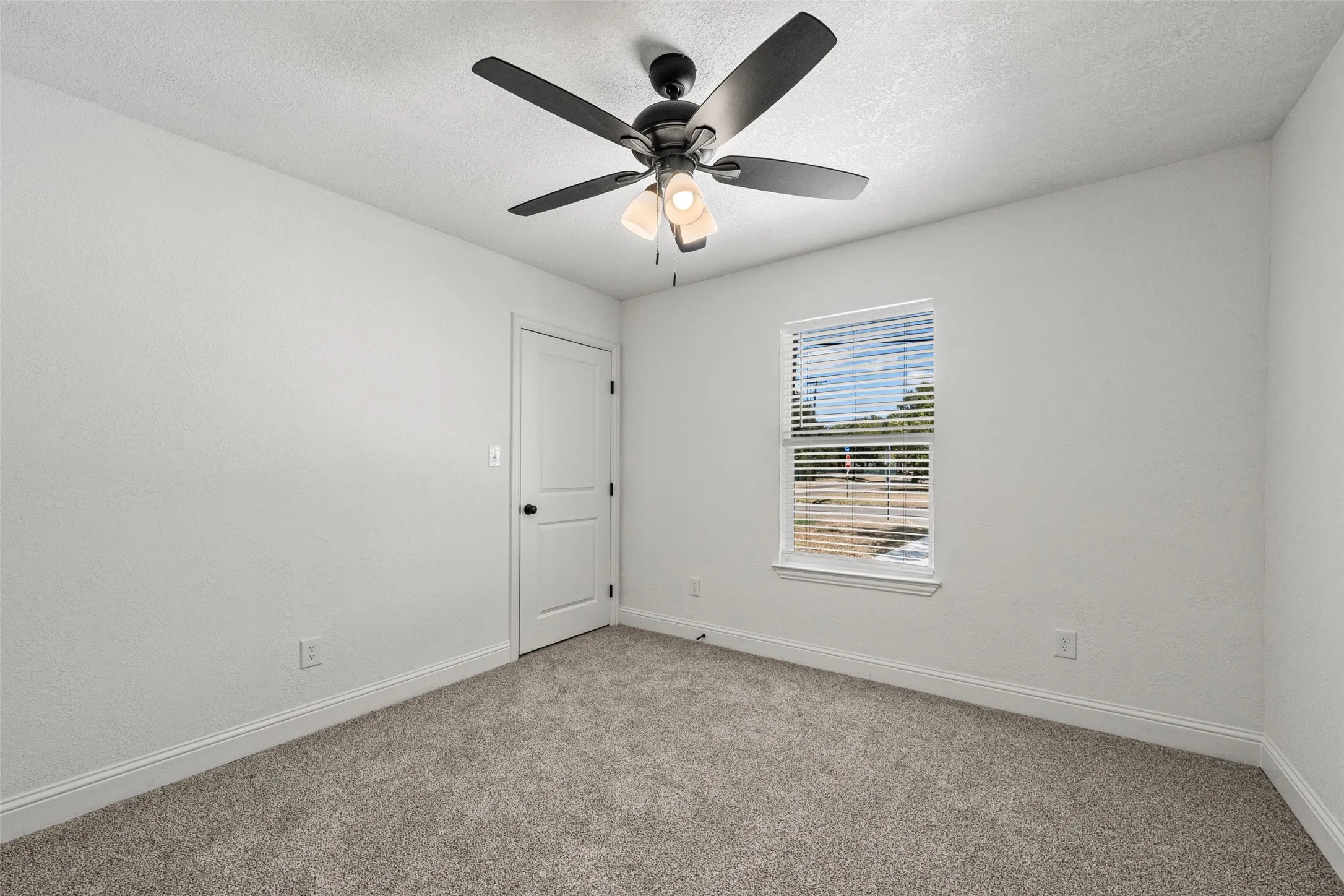Neutral wall finishes, recessed window with blinds, ceiling fan with integrated lighting, and carpeted flooring
