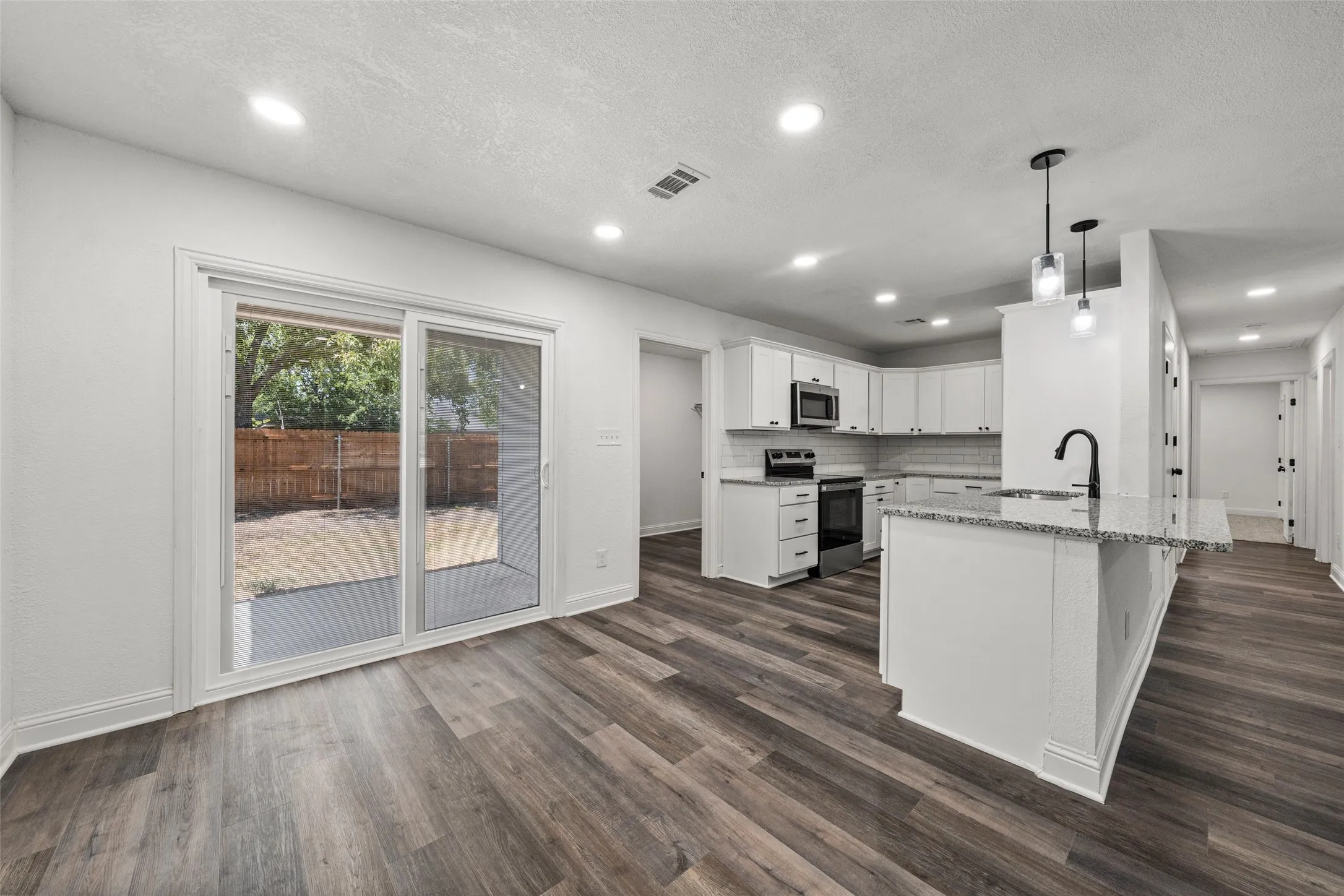 Kitchen featuring white cabinetry, granite countertops, stainless steel appliances, and a subway tile backsplash