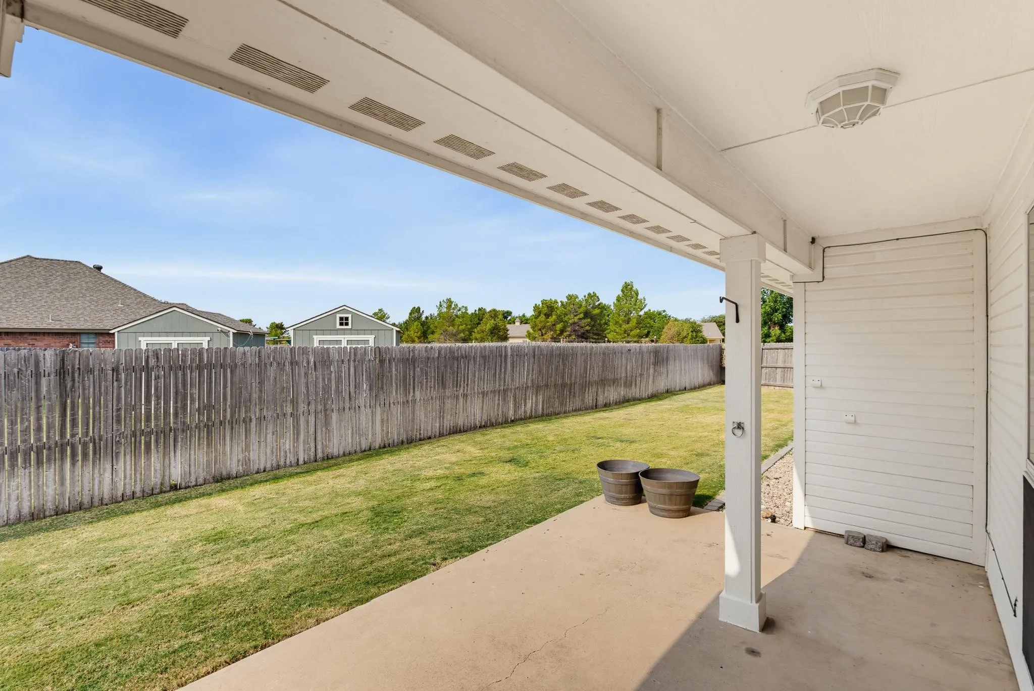 Expansive backyard with mature landscaping, wooden privacy fencing, and lush lawn space