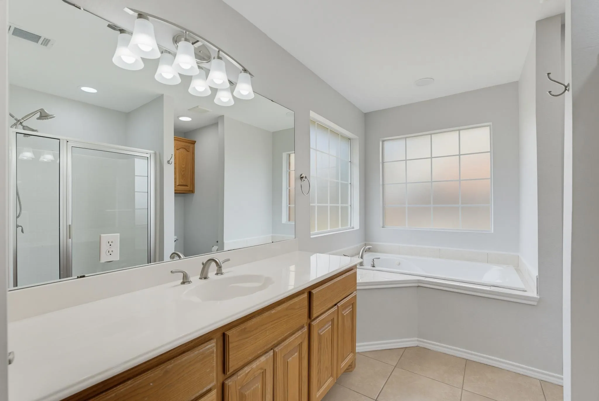 Dual-sink vanity with a light-toned countertop, brushed nickel fixtures, and wood-finish cabinetry