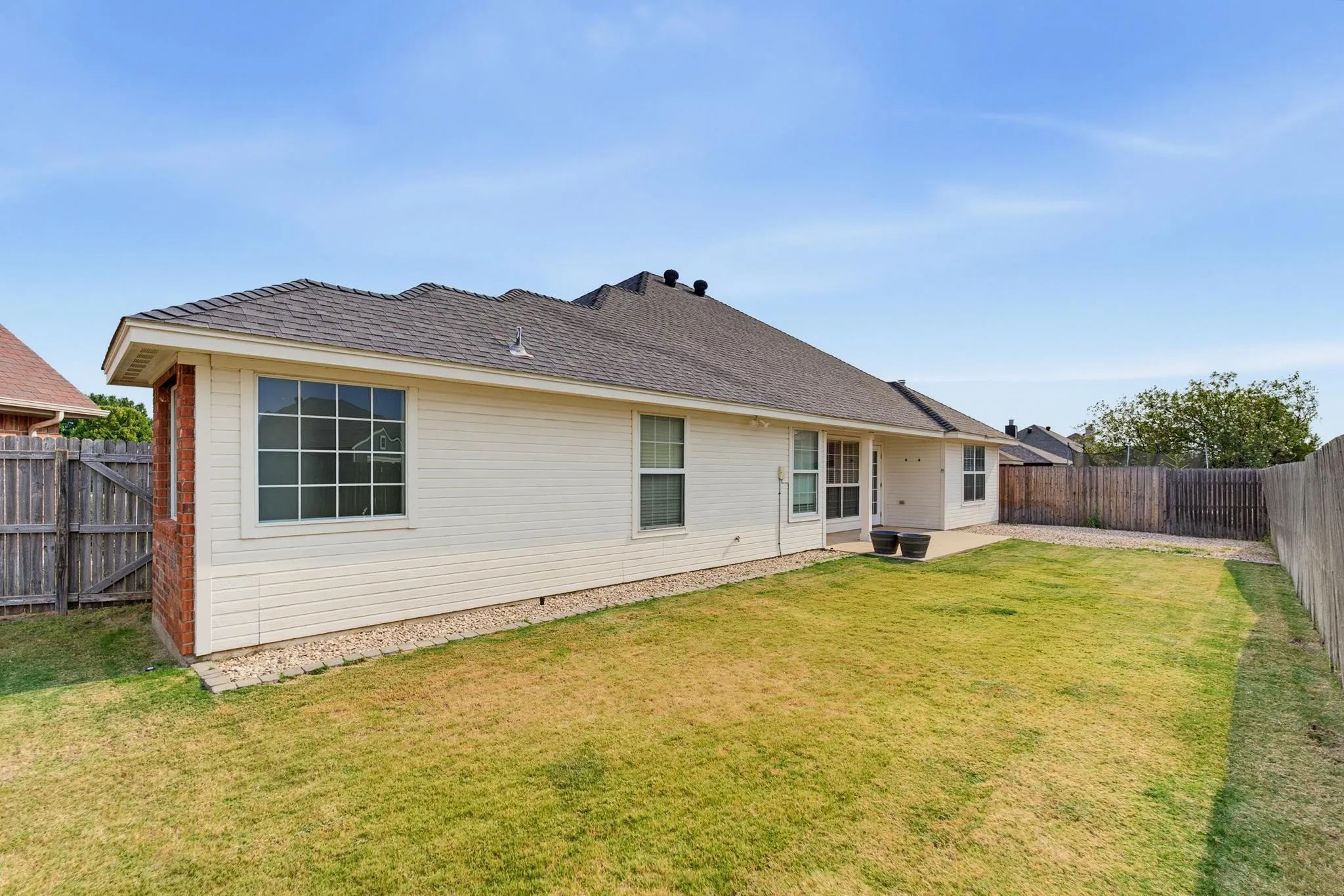 Spacious single-story home featuring a large picture window, cream-colored siding, and a charcoal-toned asphalt roof