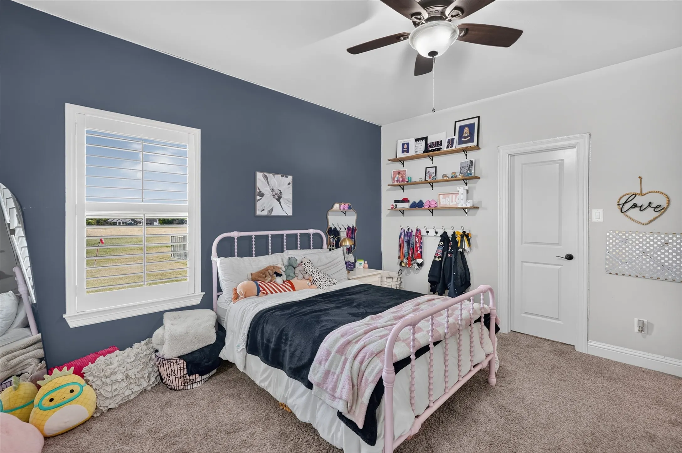 Room featuring carpet flooring, a ceiling fan with integrated lighting, a white paneled door, and a single window with white louvered blinds