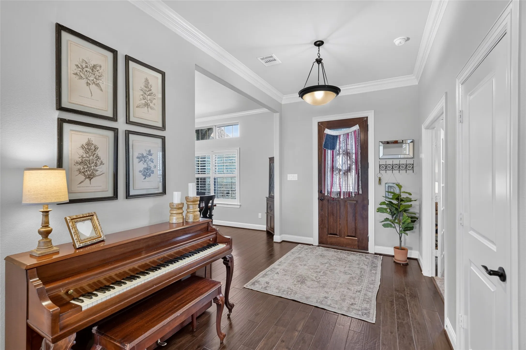 Elegant foyer showcasing dark wood-finish flooring, coffered ceiling detail, and a pendant light fixture