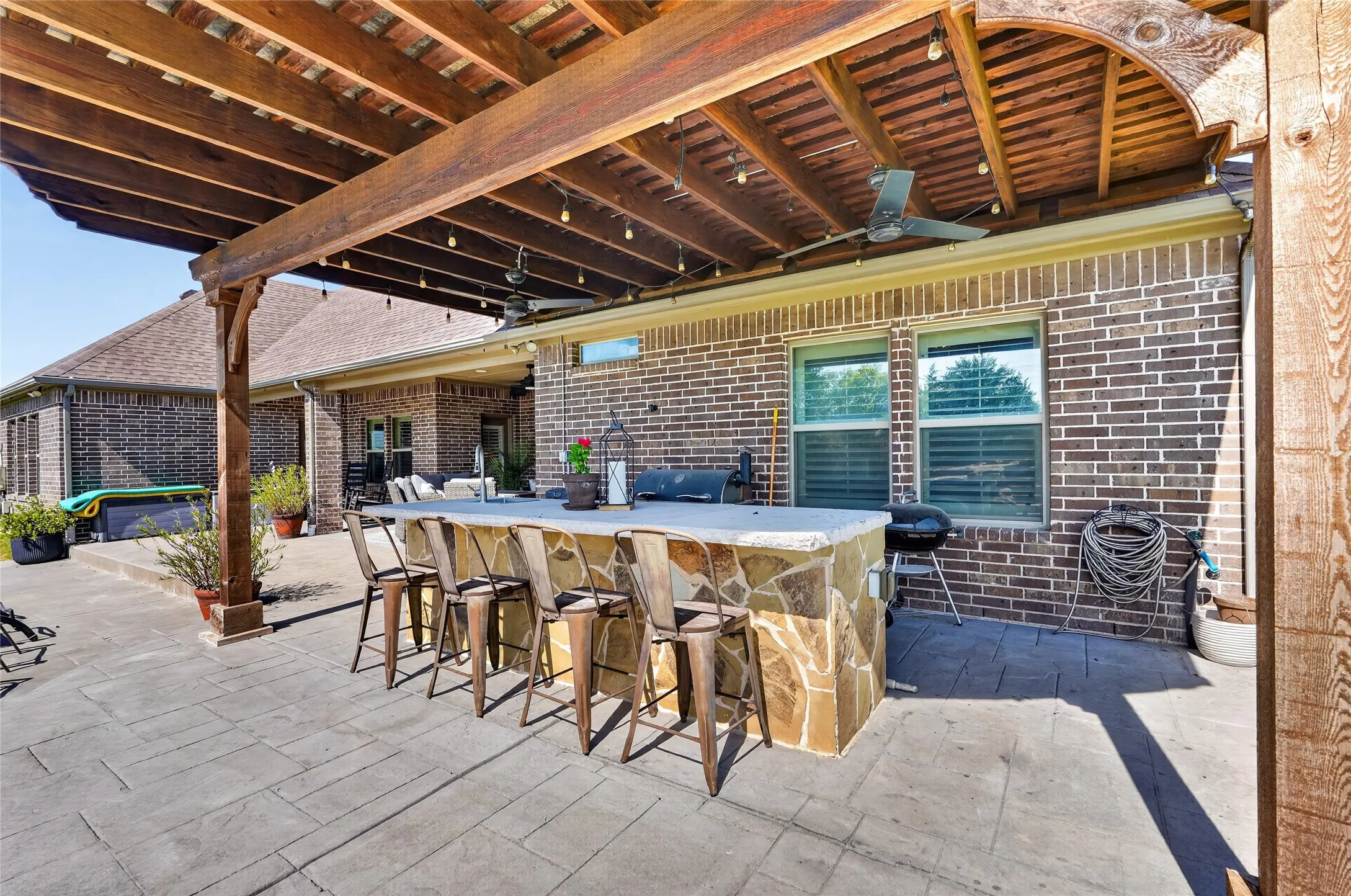 Expansive stamped concrete patio with a built-in outdoor bar featuring a stone facade and light-colored countertop