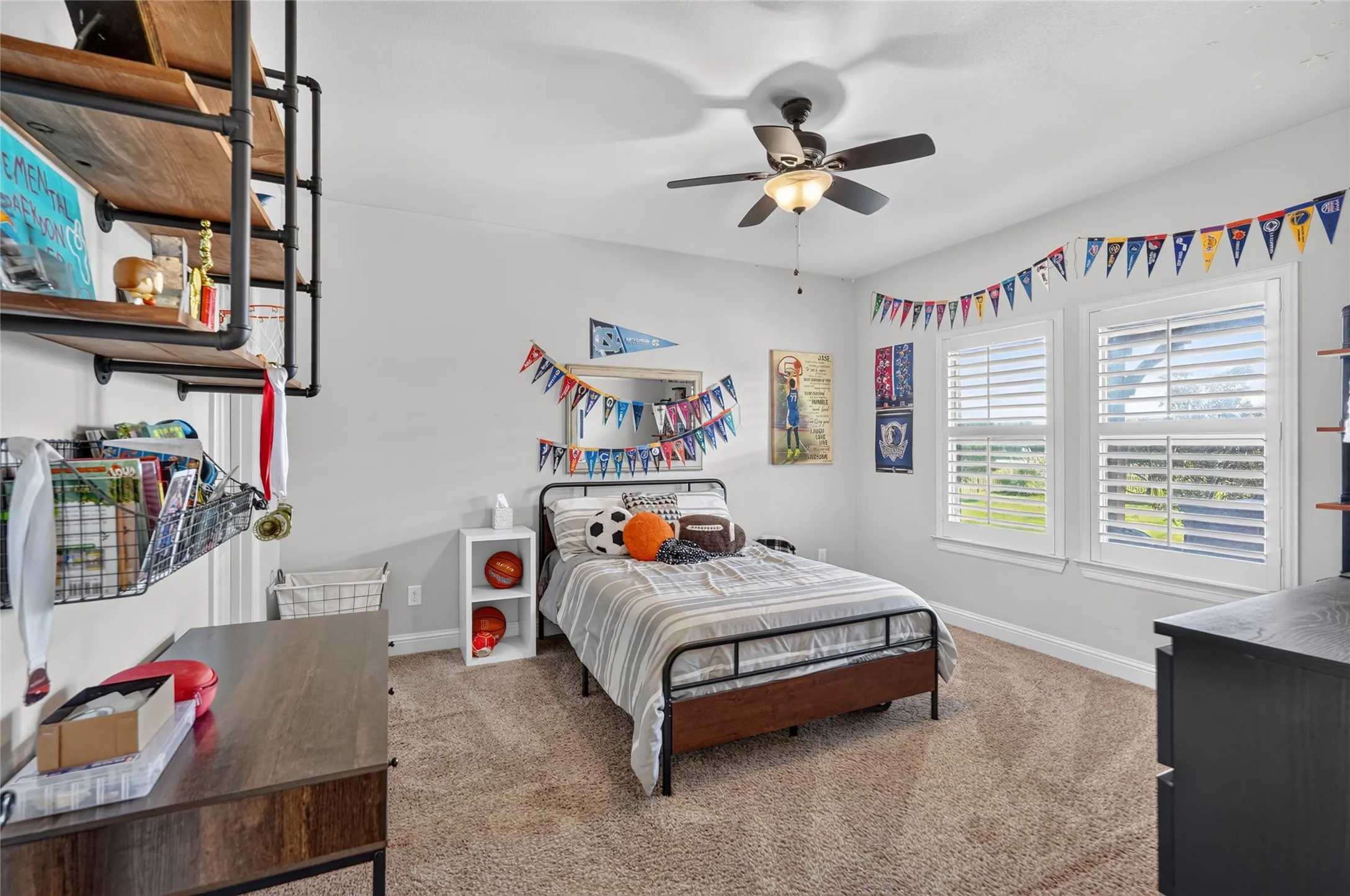 Bright bedroom with ceiling fan, carpet flooring, and abundant natural light from large windows with plantation shutters