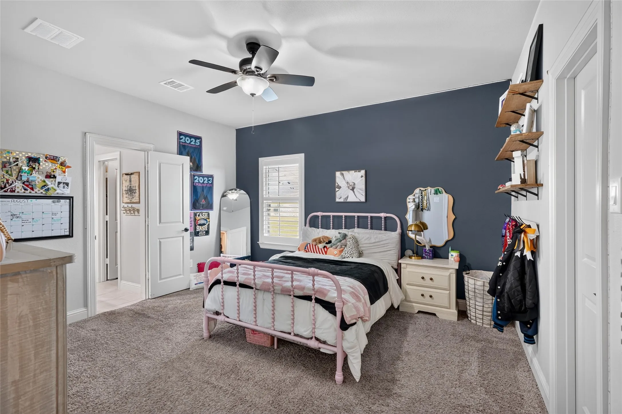 Spacious bedroom featuring neutral carpet flooring, soft white ceiling fan with integrated lighting, and crisp white trim throughout