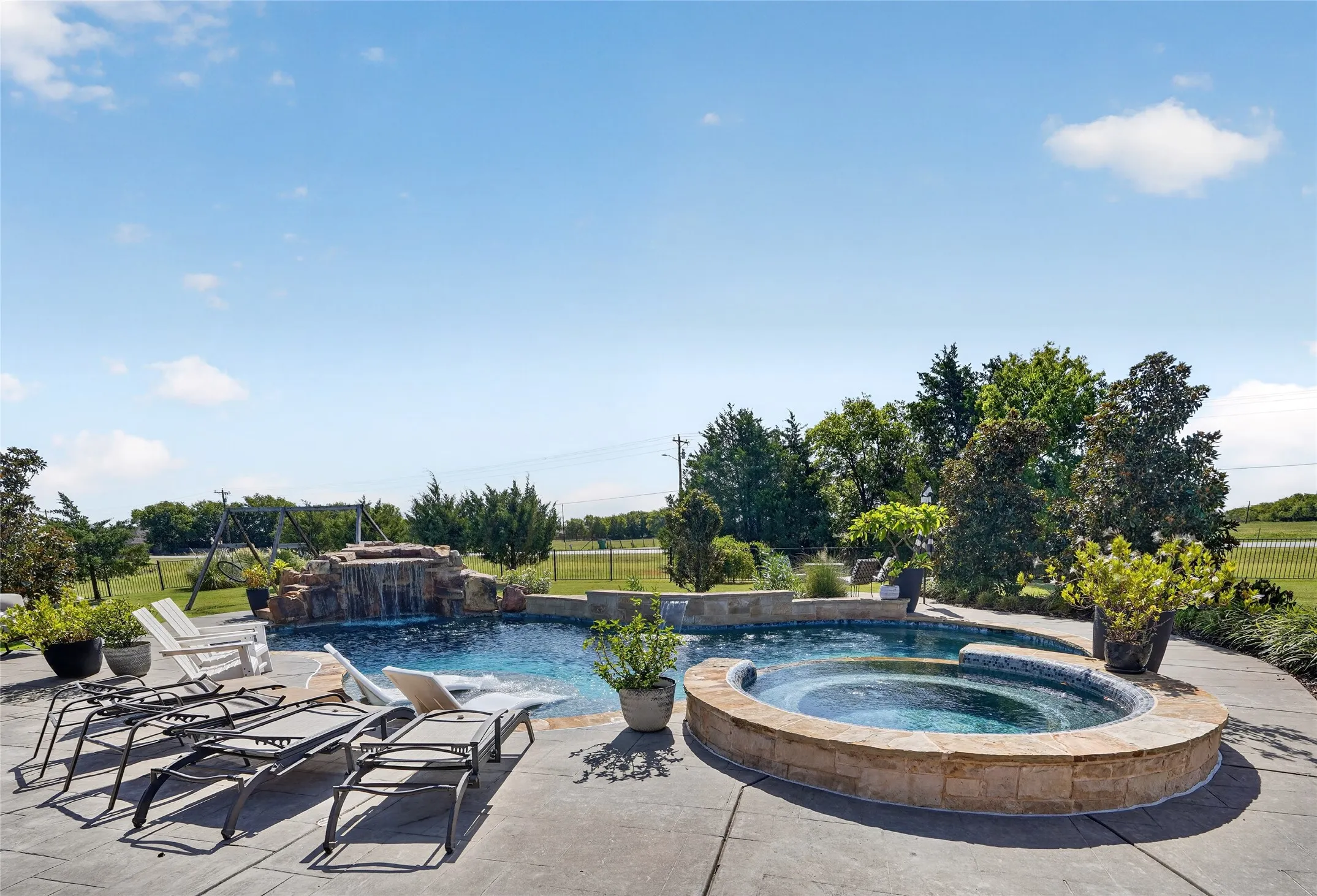 Expansive outdoor entertainment area featuring a resort-style swimming pool with integrated spa, curved stone surround, and lounge seating