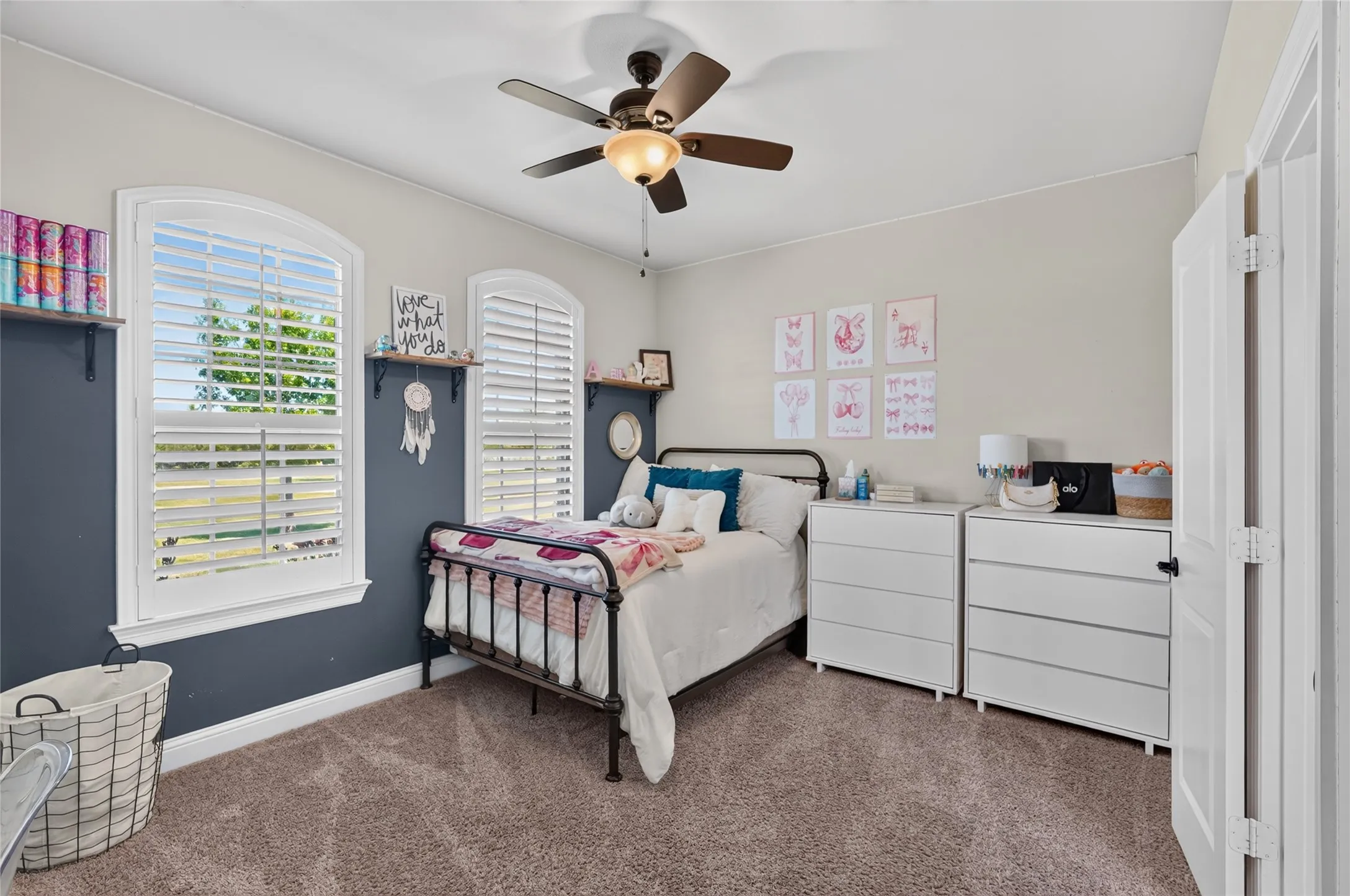 Arch-top windows with interior plantation shutters, ceiling fan with integrated lighting, and carpet flooring
