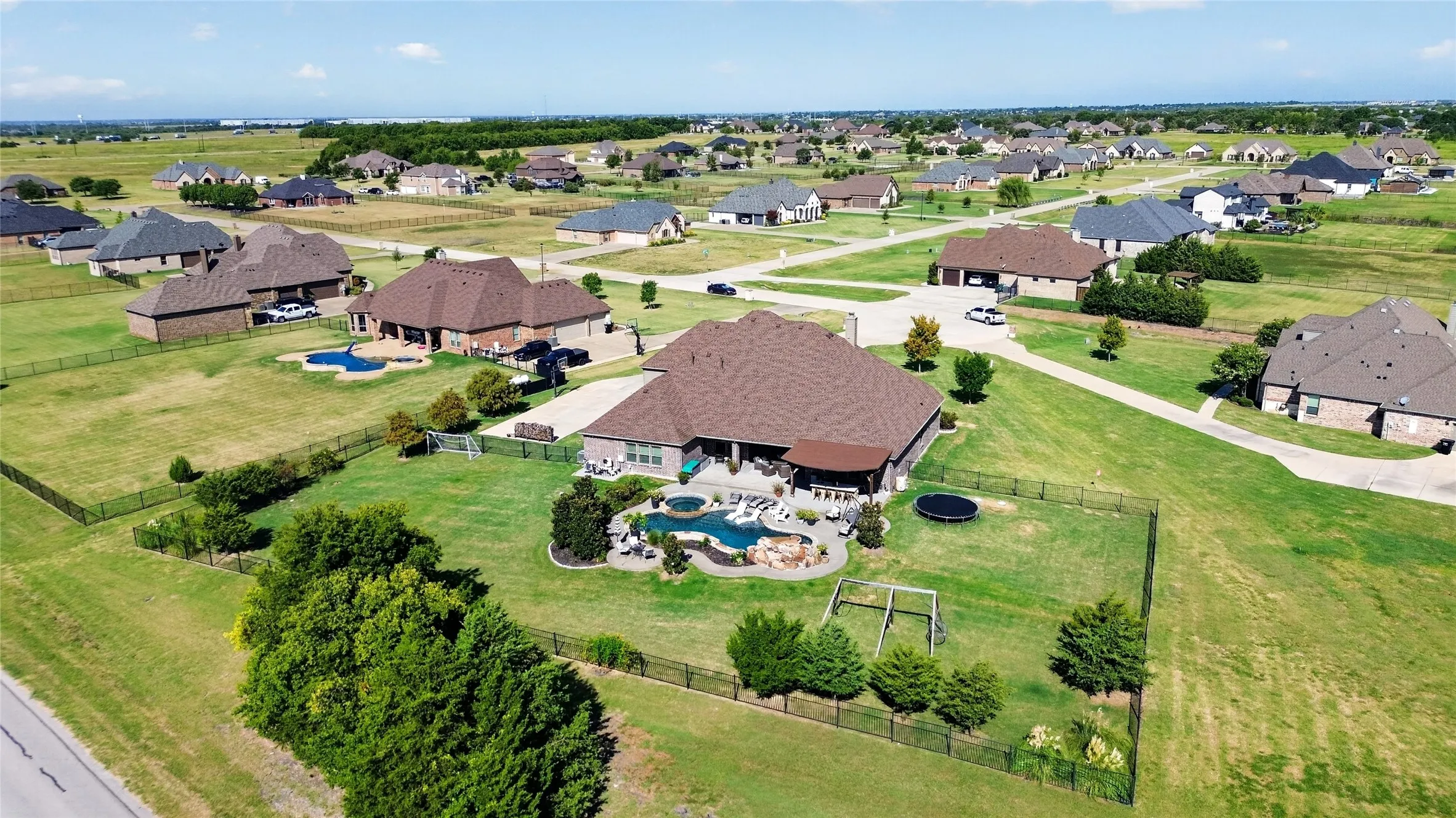 Expansive fenced backyard with a custom-shaped swimming pool, integrated spa, and an attached covered patio