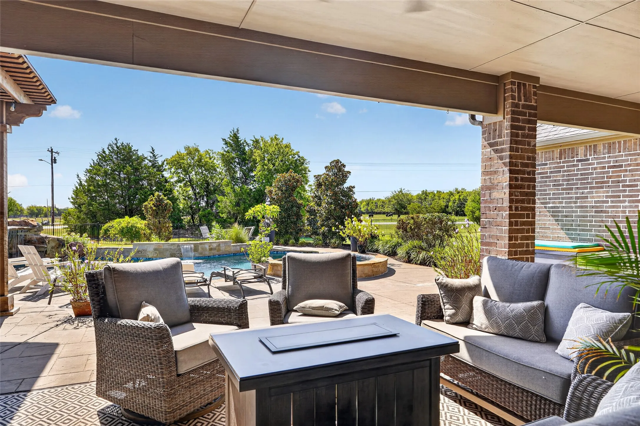 Covered patio with brick columns, stone paver flooring, and a built-in pool featuring a waterfall