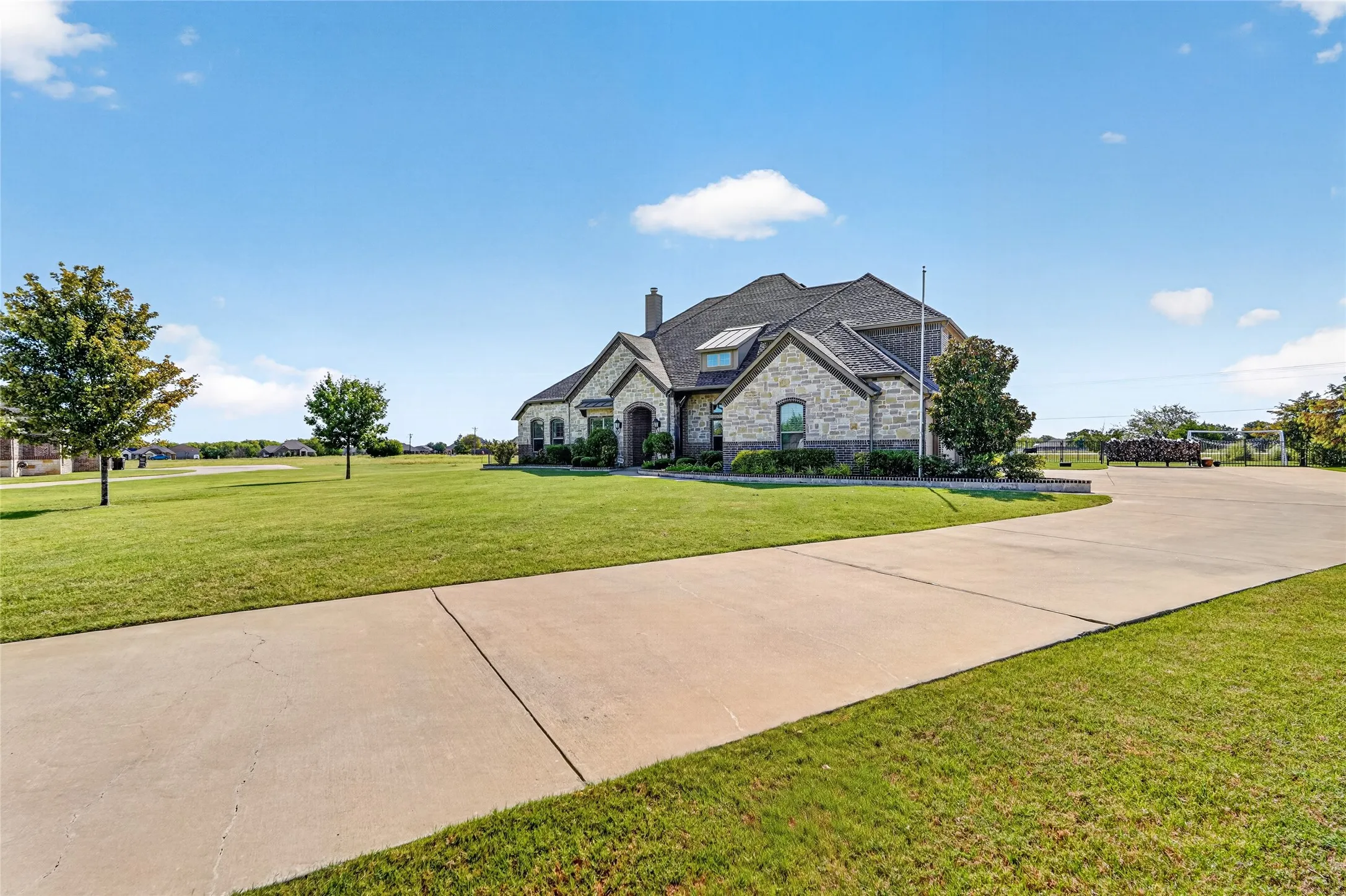 Stunning two-story residence set on expansive grounds featuring a manicured lawn, mature landscaping, and a long concrete driveway