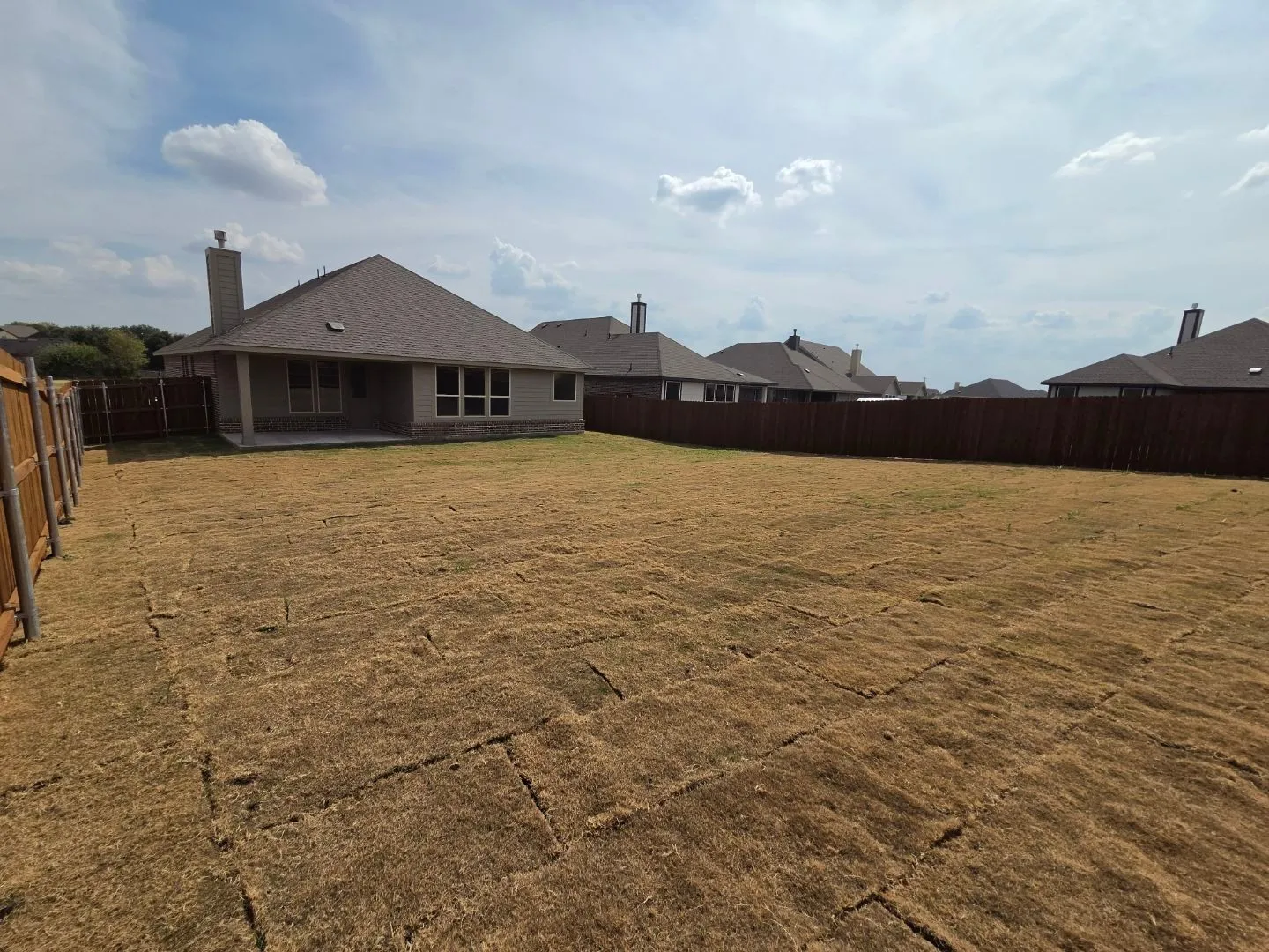 Expansive backyard with a full privacy fence, a concrete patio, and a stone and siding exterior