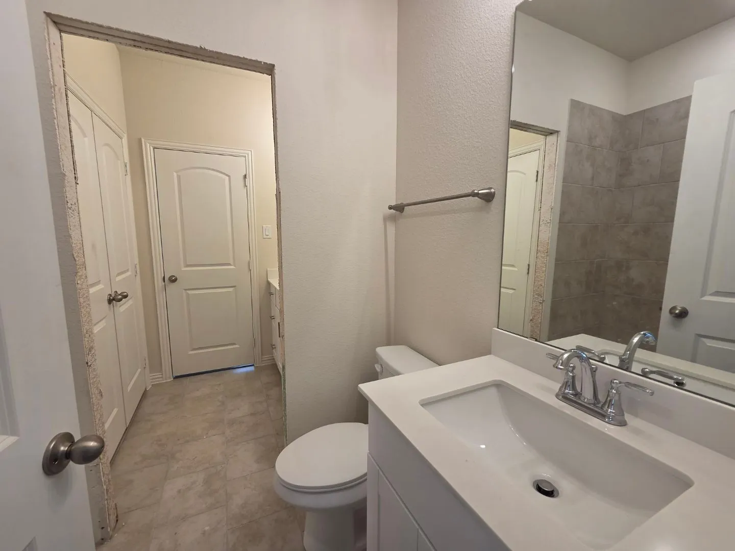 White vanity with integrated sink, chrome faucet, and rectangular mirror