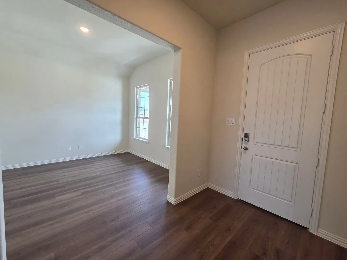 Entry with wood-finish flooring, paneled door, and recessed lighting