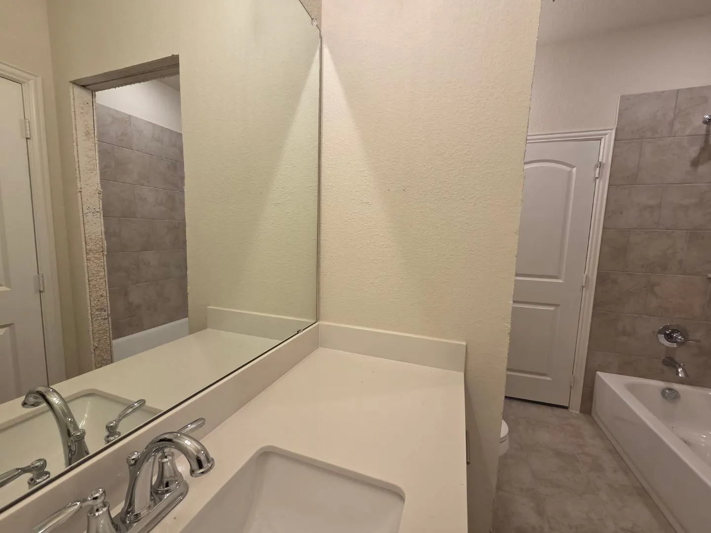 Vanity with an integrated sink, polished chrome faucet, and expansive mirror